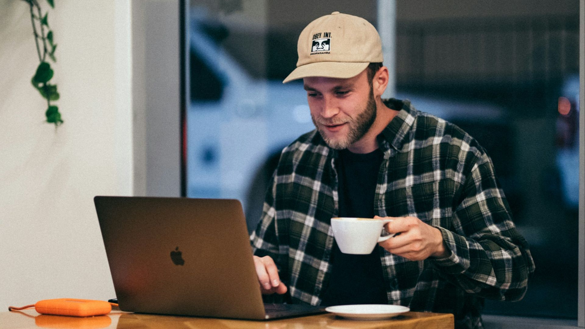 man sitting while having coffee and using laptop