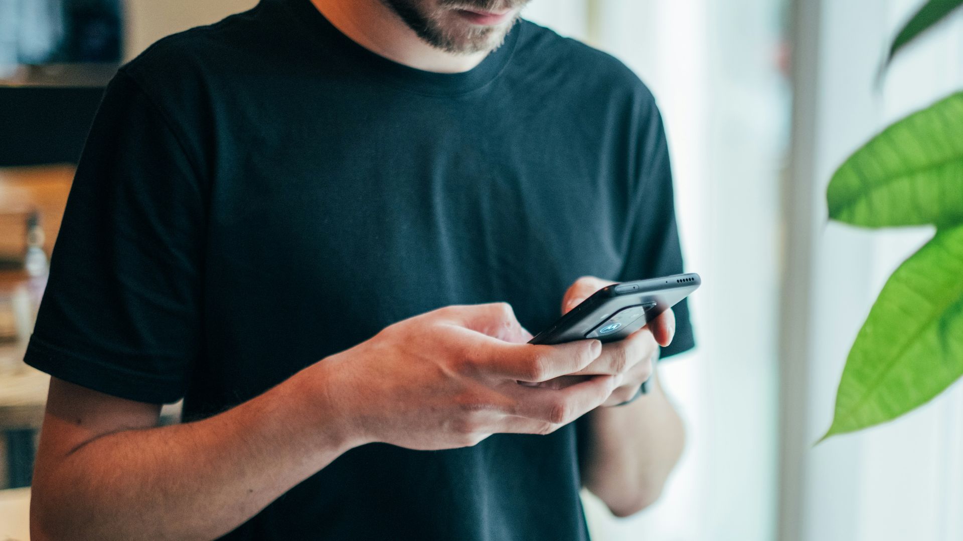 man in black crew-neck top using smartphone