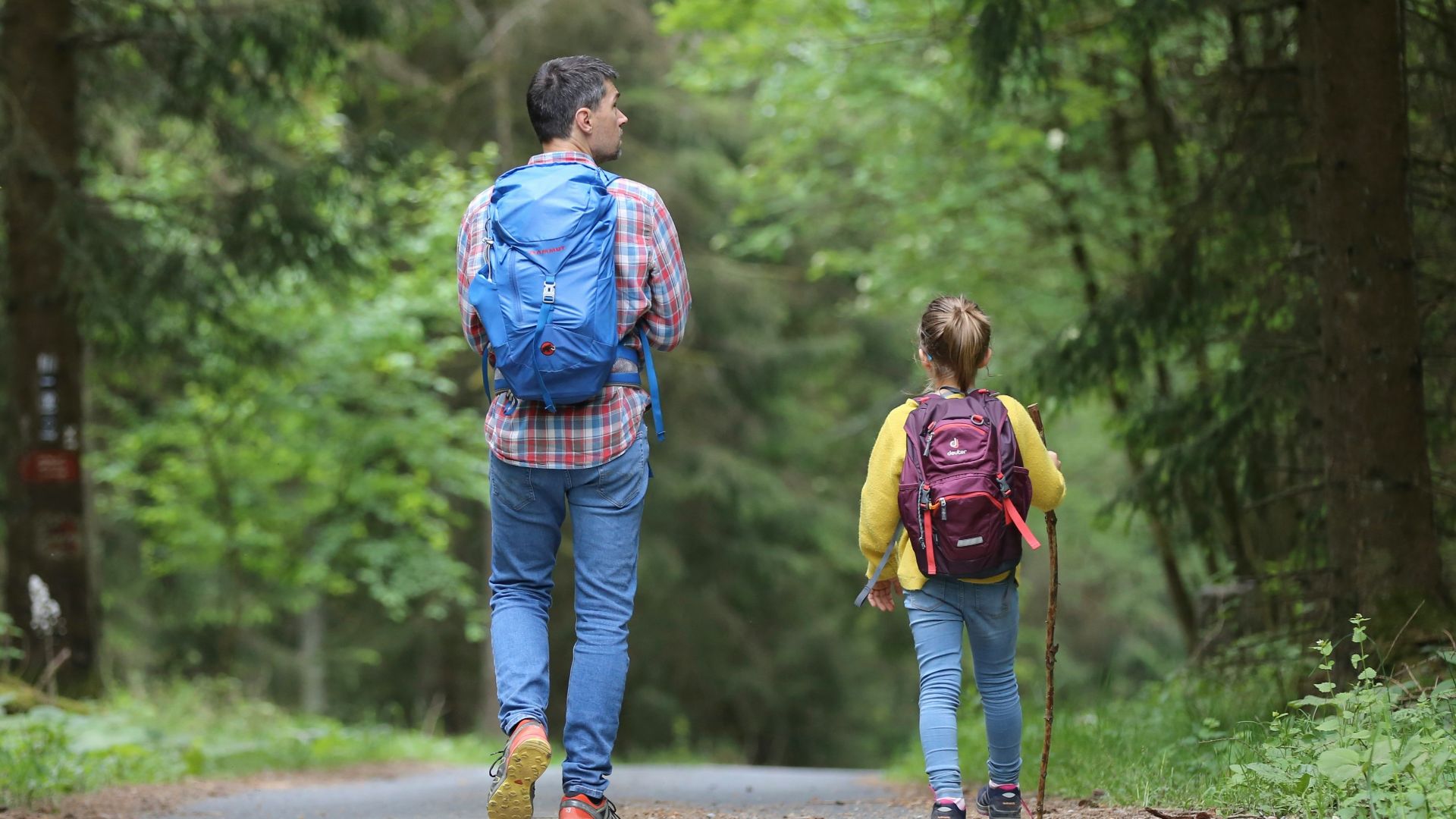 man in blue jacket and blue denim jeans walking on dirt road during daytime