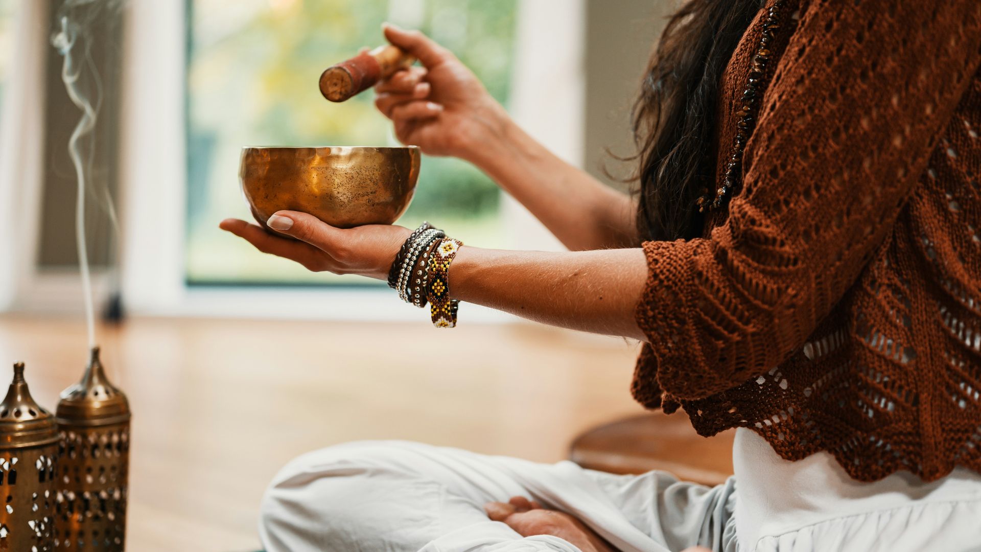 woman in brown knit sweater holding brown ceramic cup
