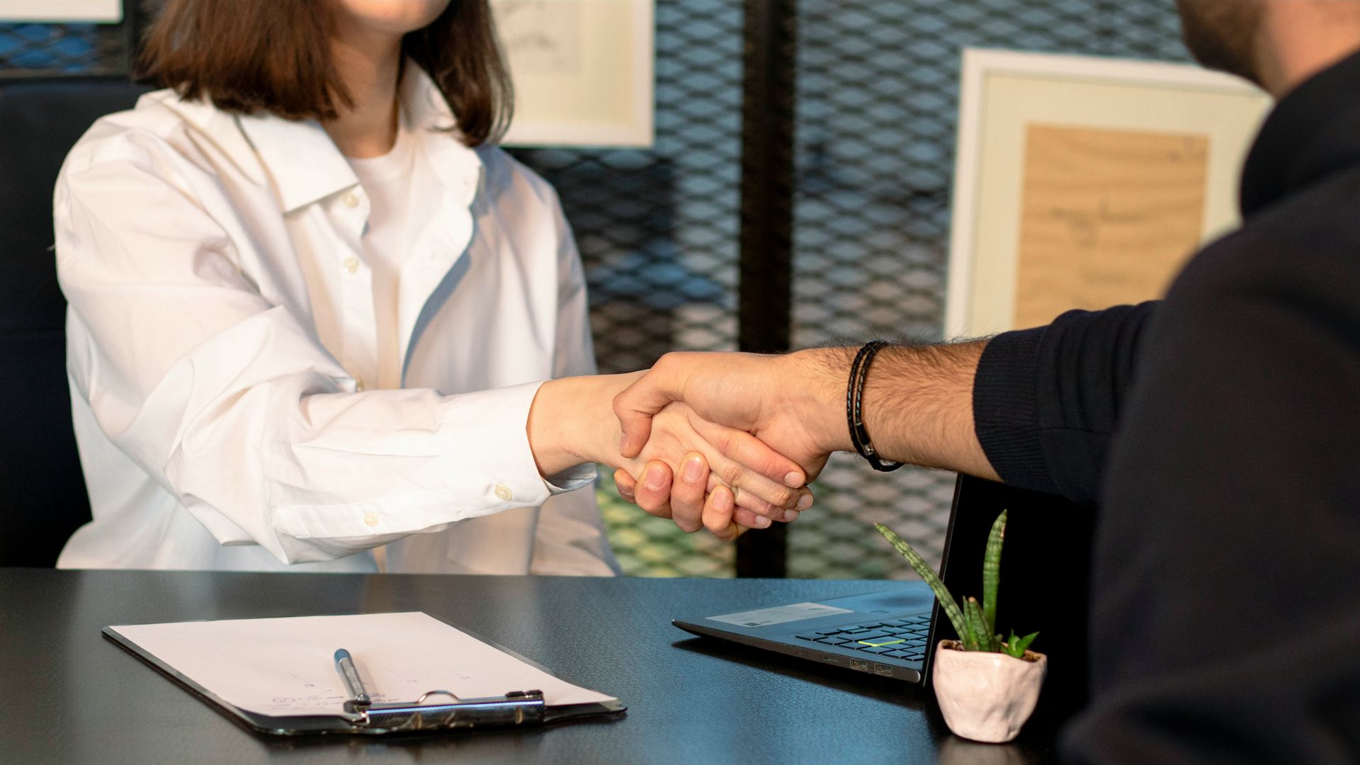 a man and a woman shaking hands in front of a laptop