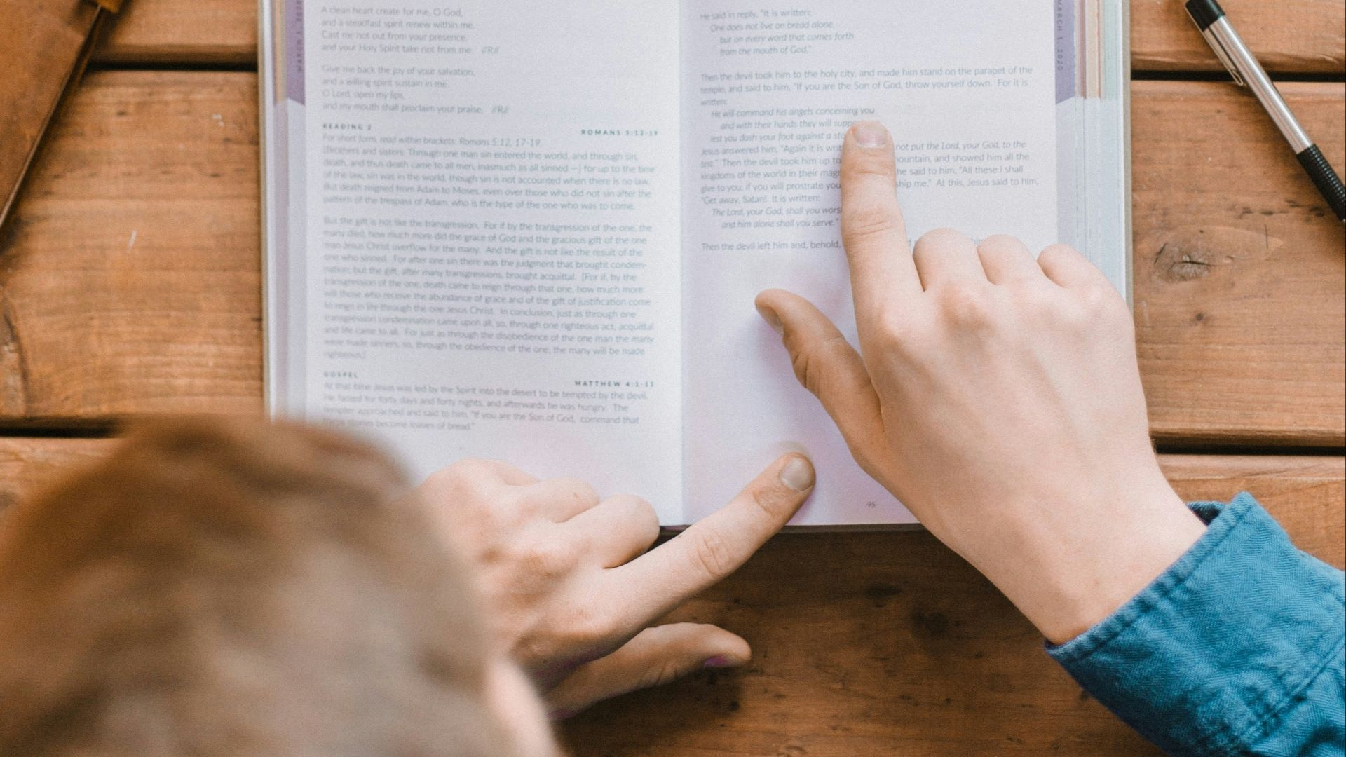 person in blue long sleeve shirt writing on white paper