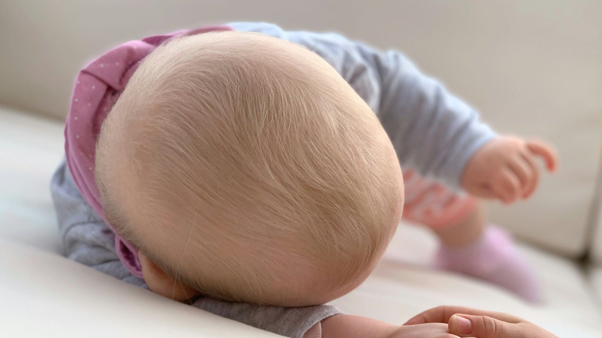 baby in blue long sleeve shirt lying on bed