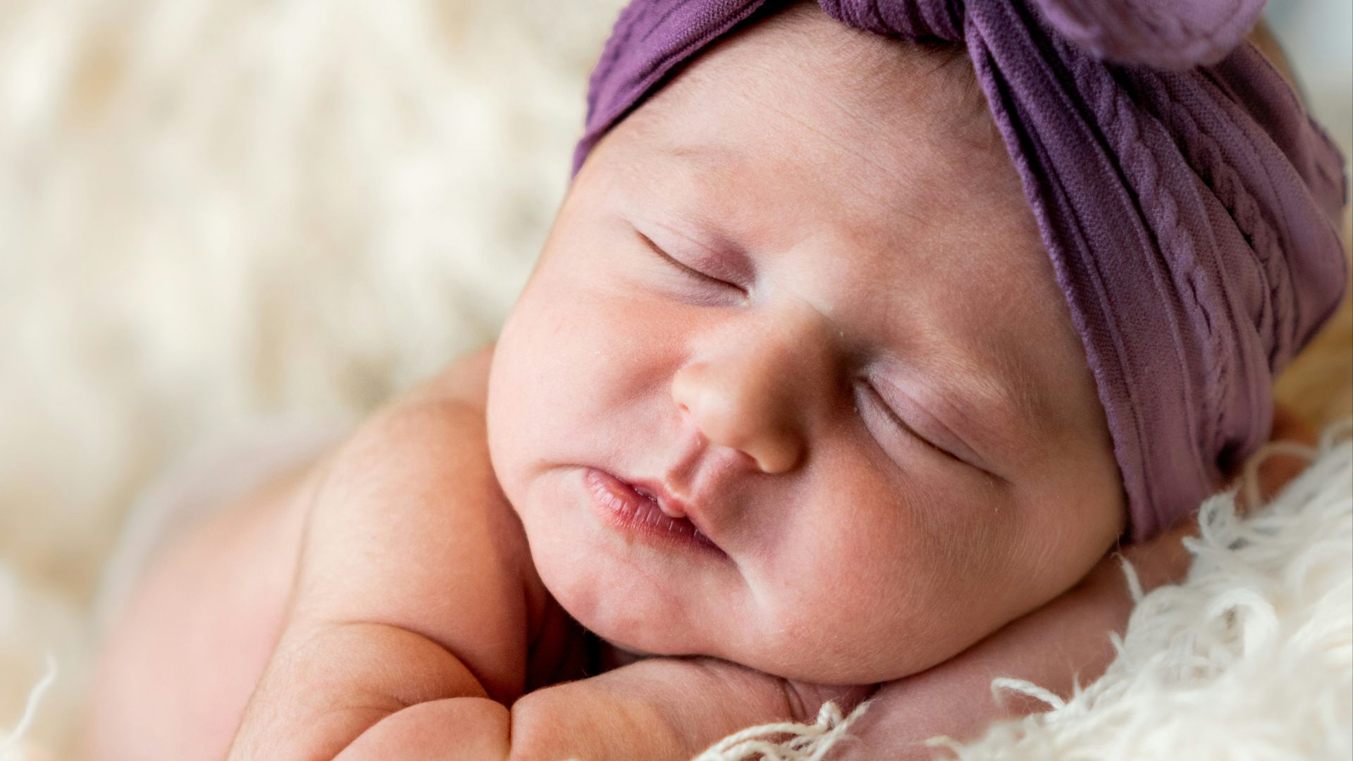 girl in white fur coat lying on white fur textile