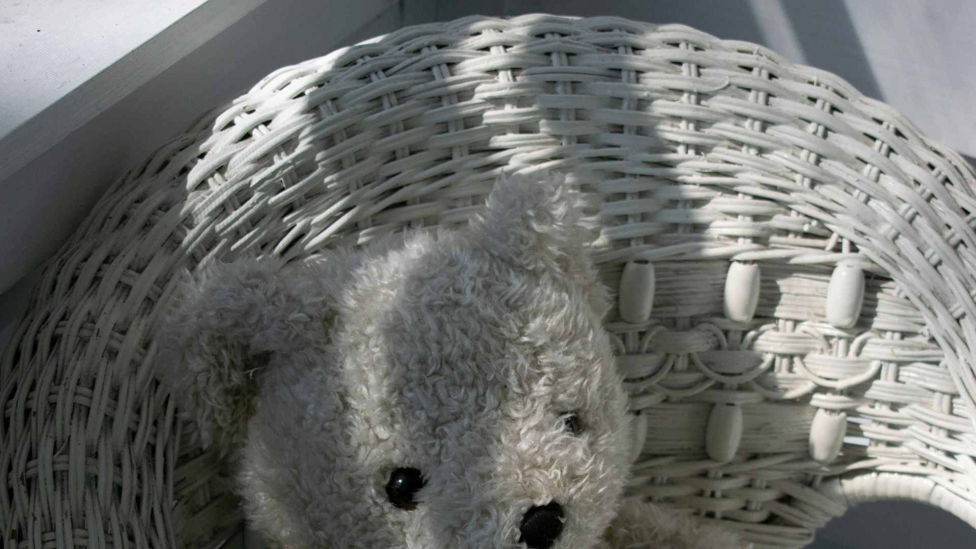 a white teddy bear sitting in a wicker chair
