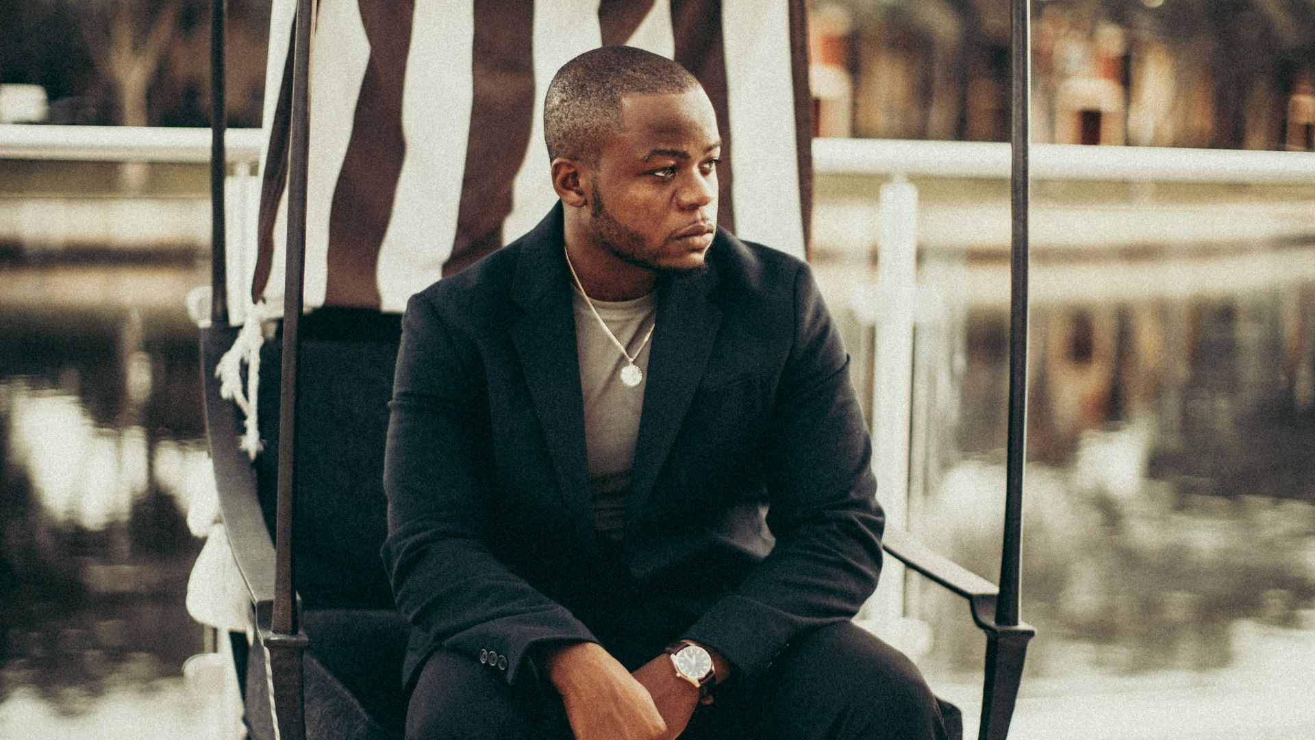 man in black suit sitting on white and blue striped chair
