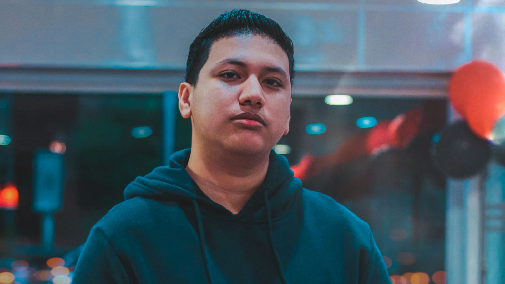 man wearing black, white, and gray hoodie holding red chair