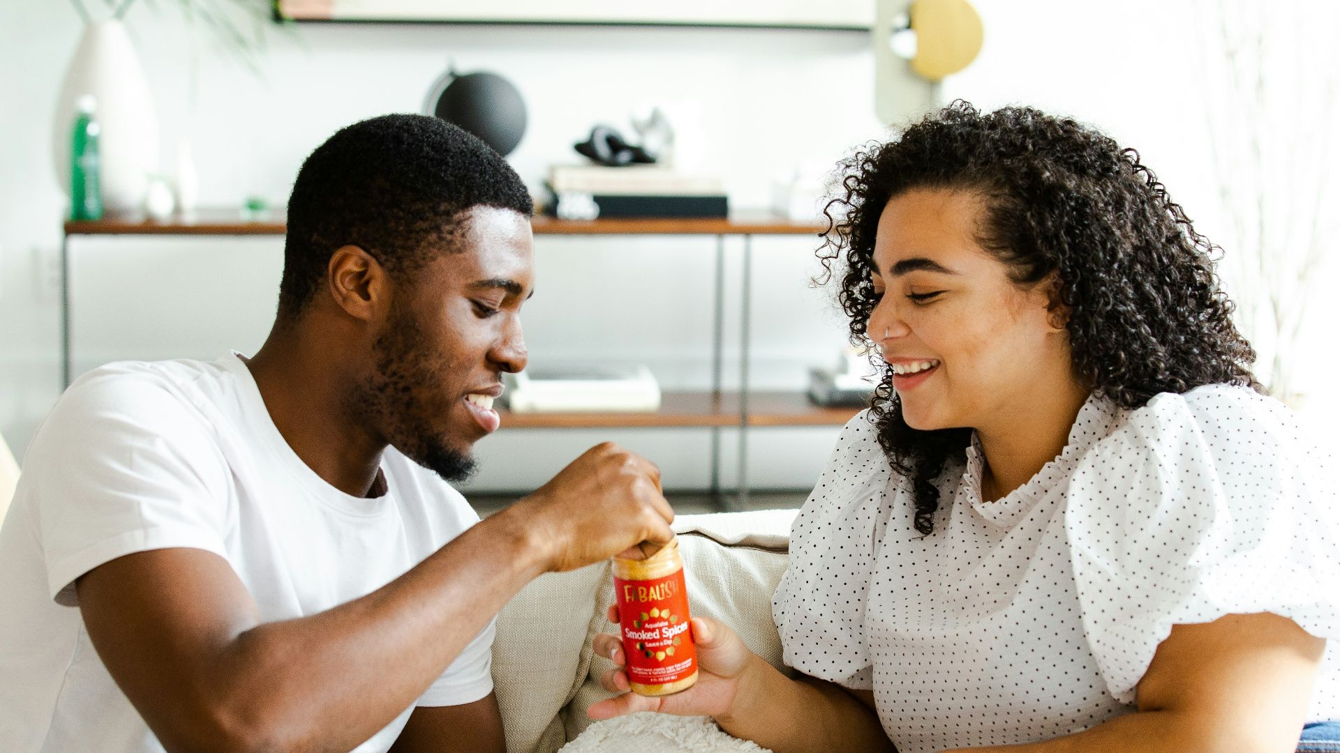 man in white crew neck t-shirt and blue denim jeans sitting on white sofa chair