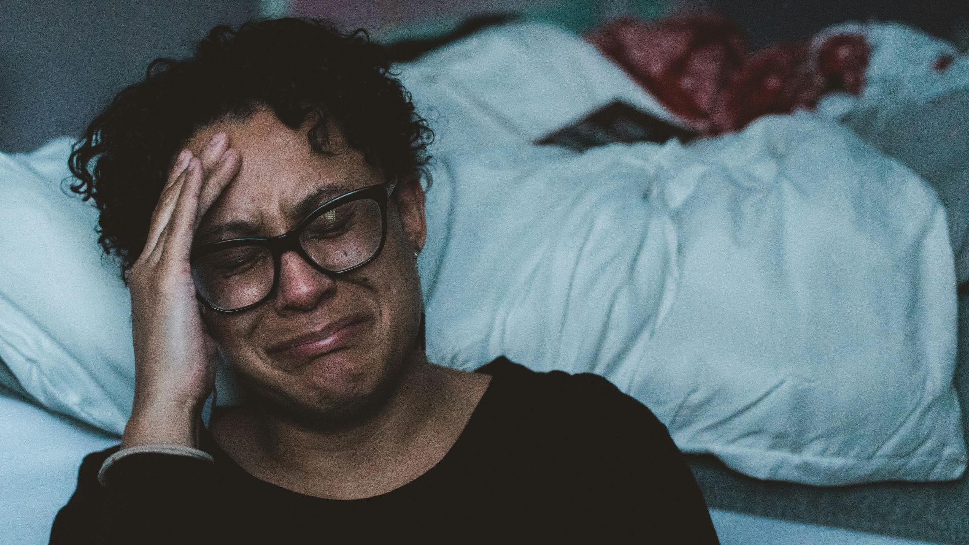 person crying beside bed