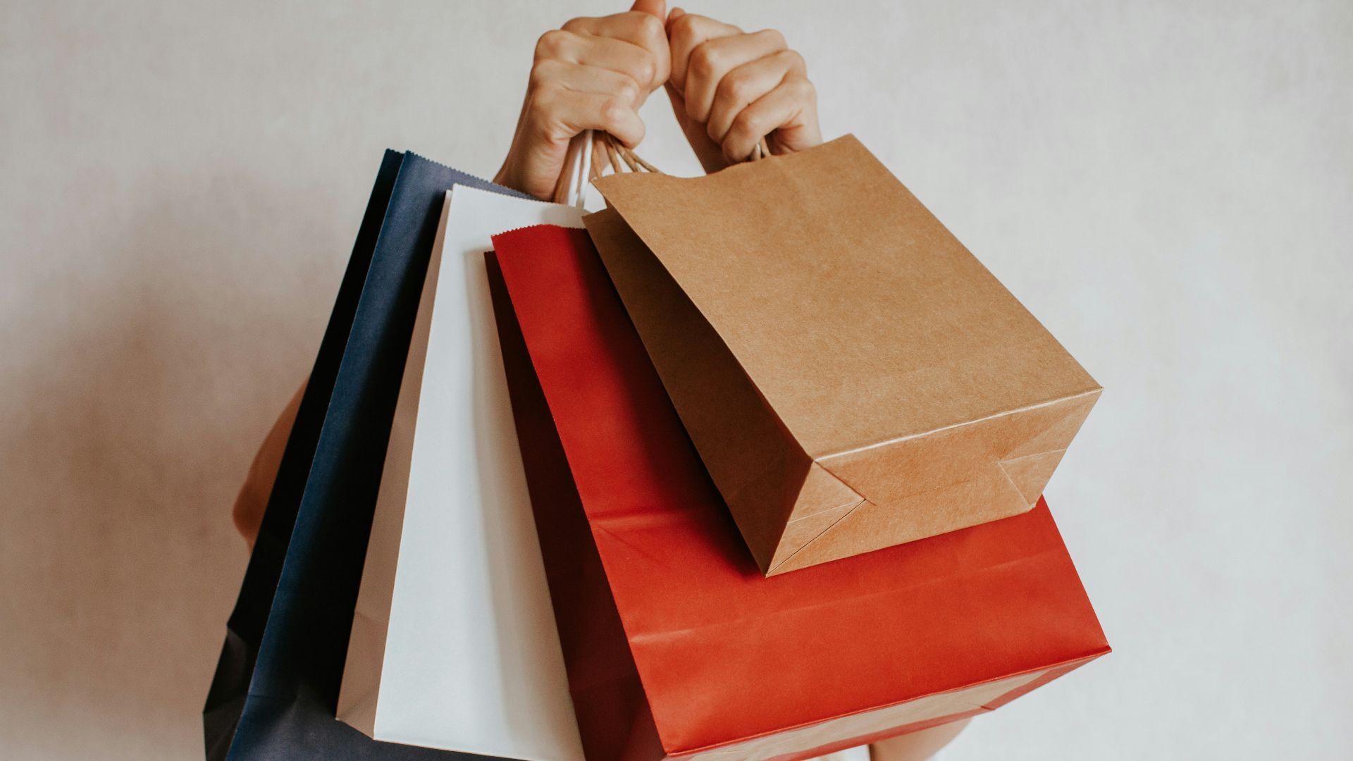 Person holding colorful shopping bags in front of face