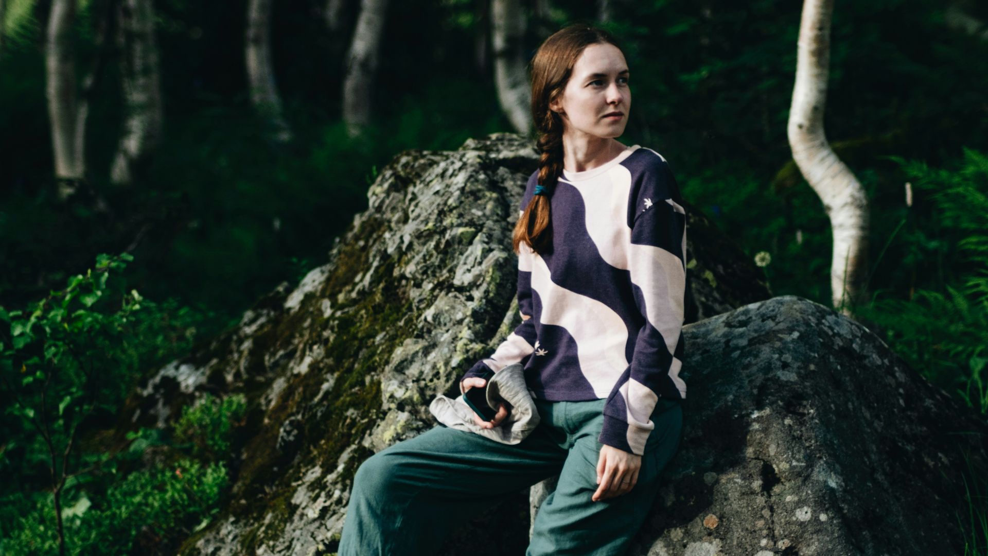 A woman sitting on a rock in the woods