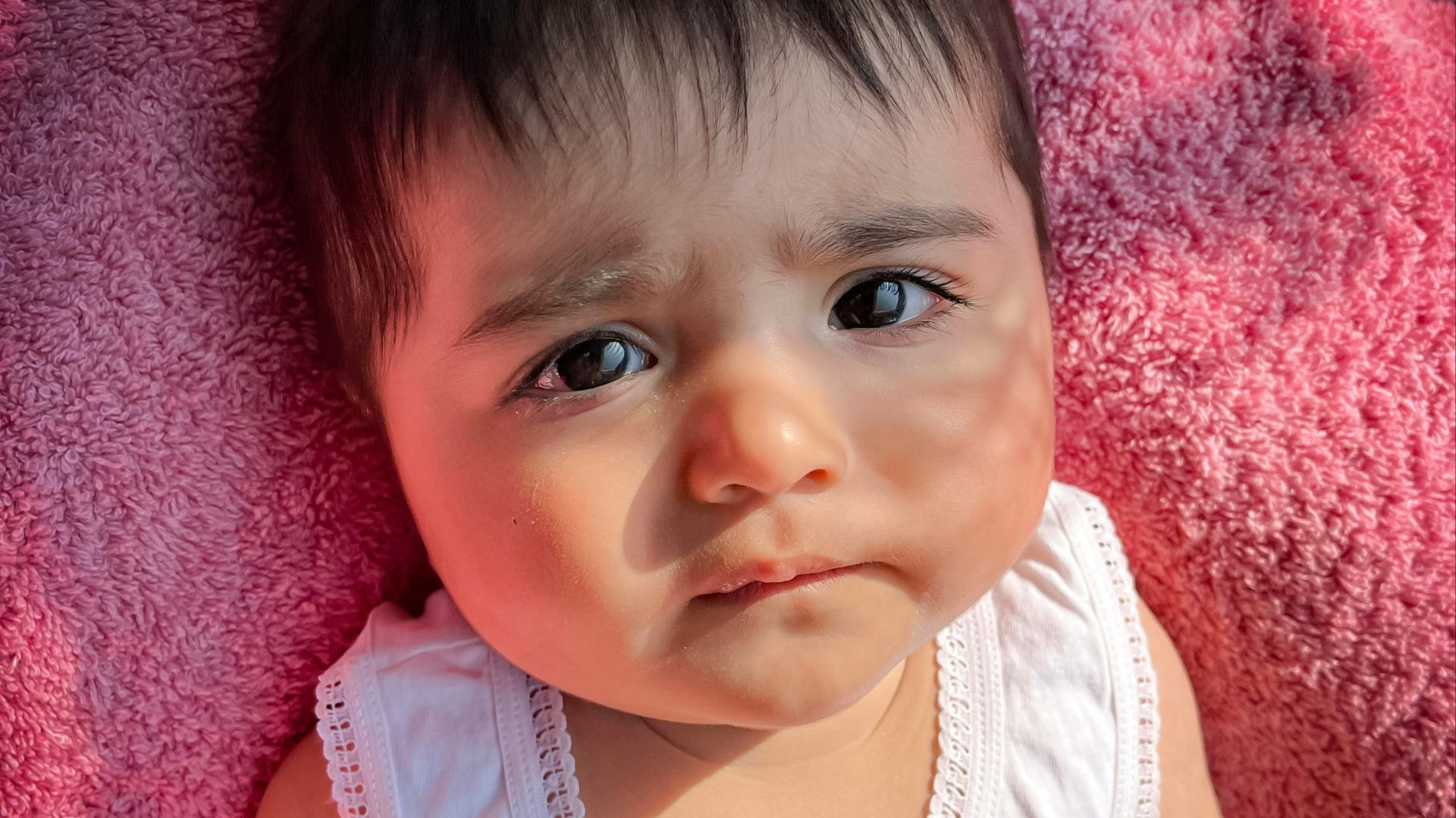 a baby girl laying on top of a pink blanket
