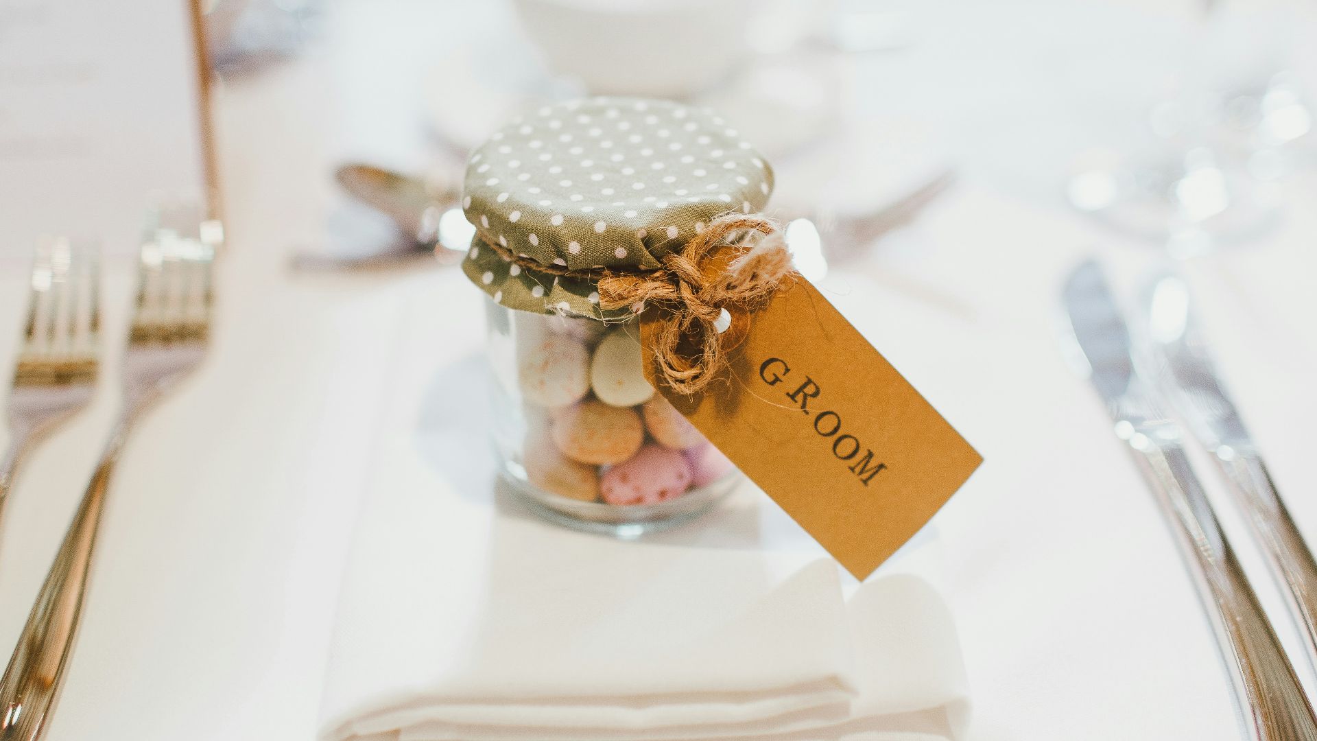 clear glass mason jar on top of white table napkin between forks and knives