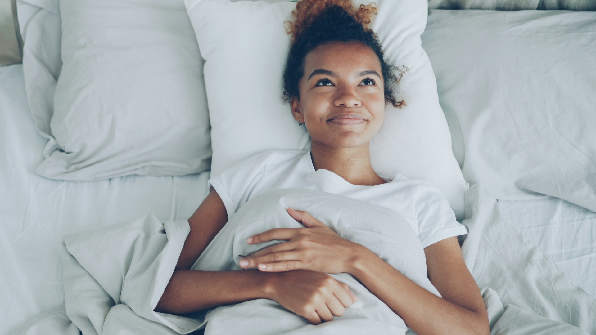 Young woman lying in a white bed
