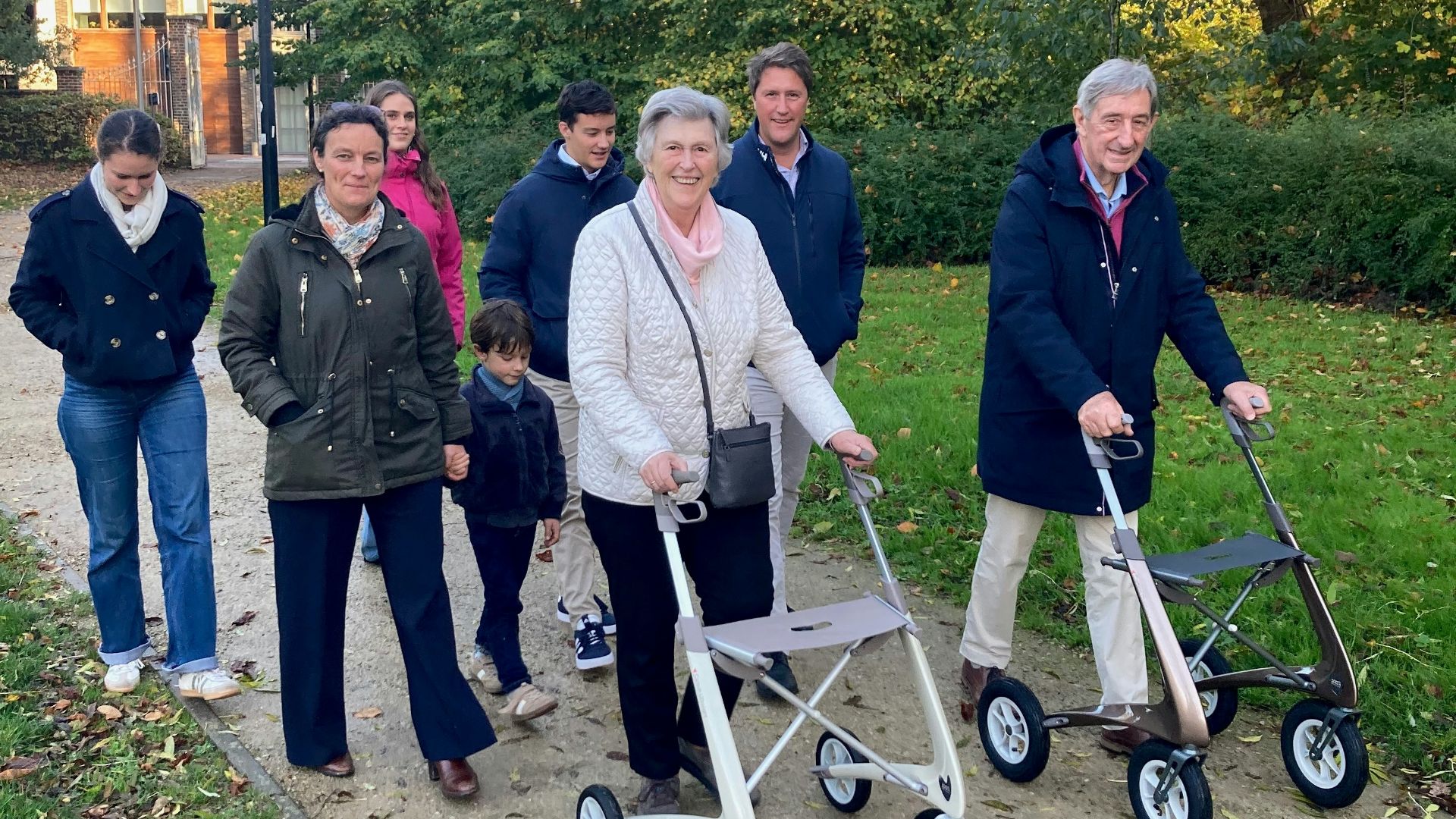 A group of people walking in a park with walkers.
