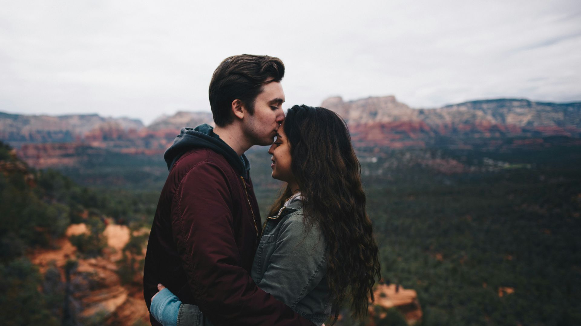 man kissing woman's forehead