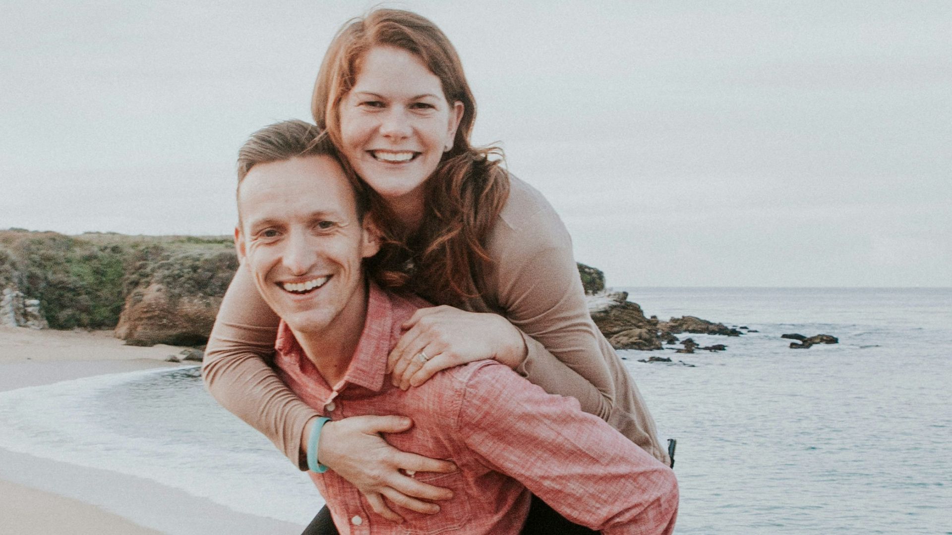 man carrying woman beside seashore