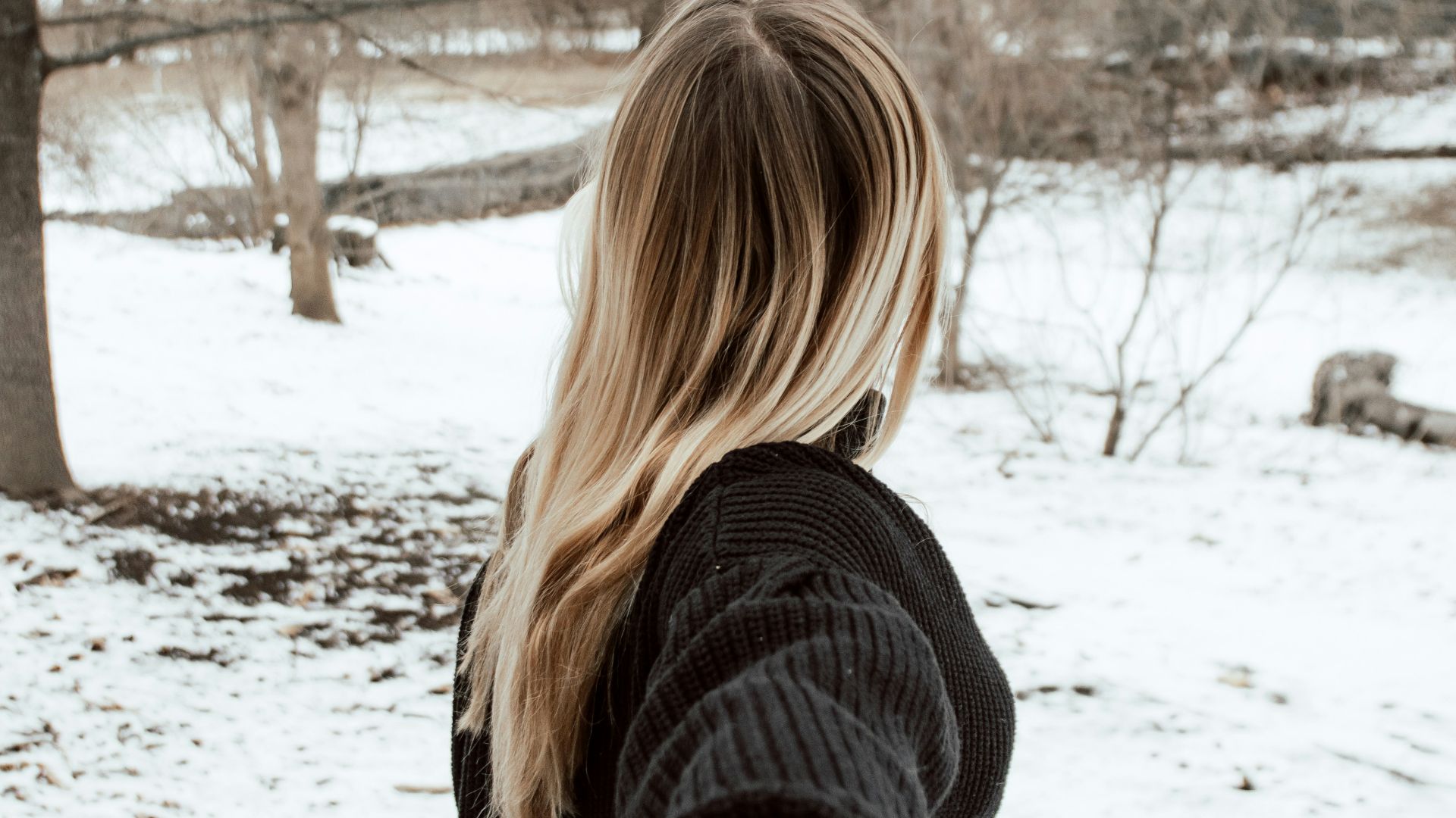 woman in black sweater standing on snow covered ground during daytime