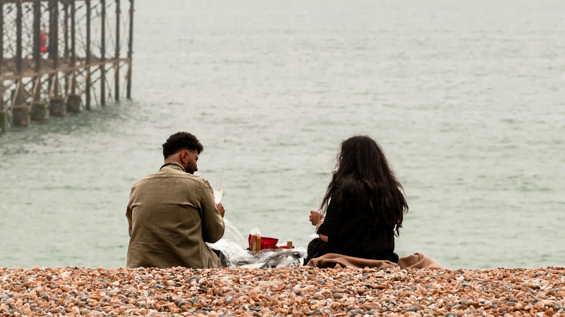 people sitting on brown sand near body of water during daytime