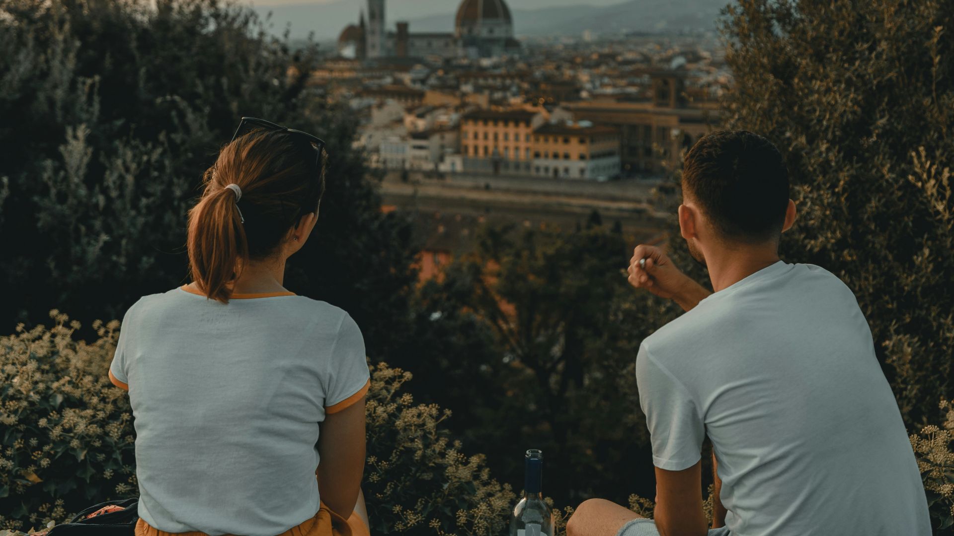 woman and man wearing white shirt while sitting near green trees during daytime