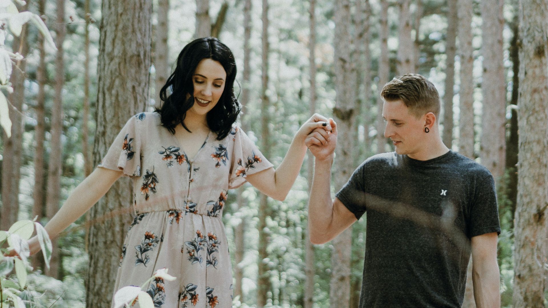 man holding hands with woman near trees