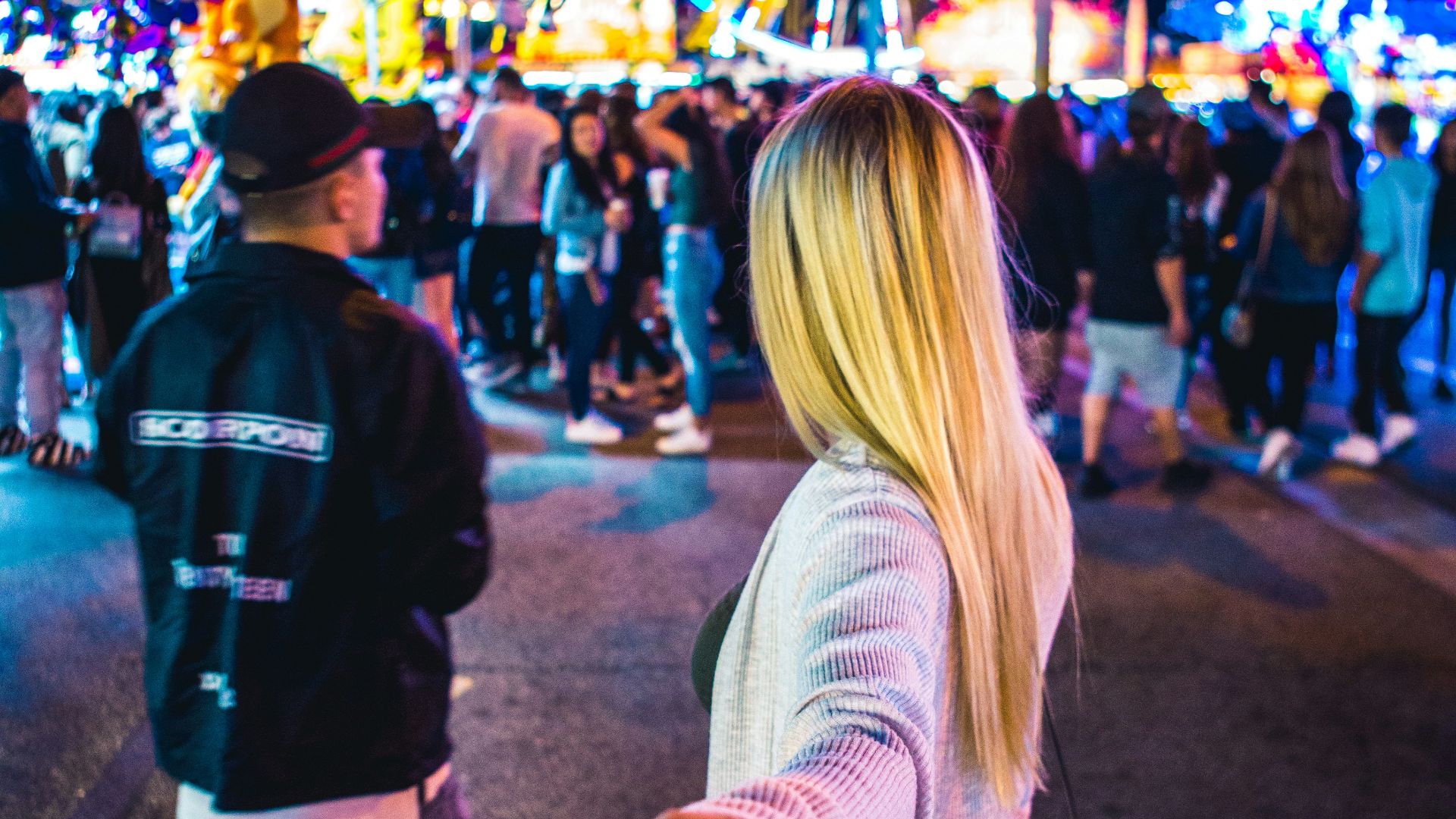 woman wearing white long-sleeved top across ferris wheel during nighttime