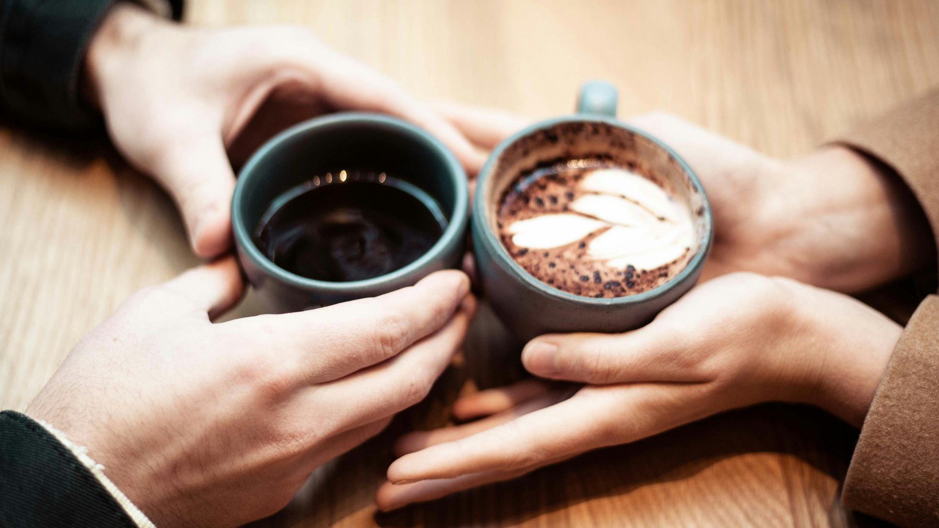 two person holding ceramic mugs with coffee