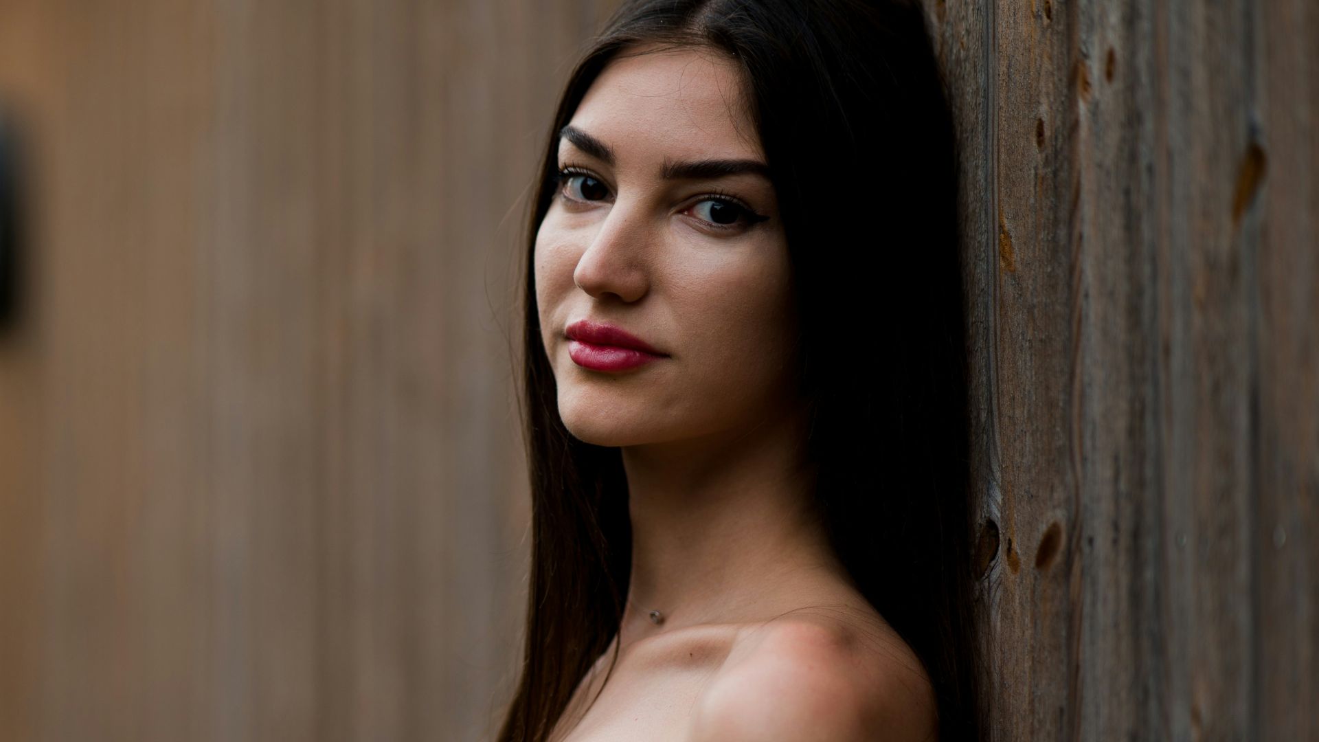 a woman leaning against a wooden wall