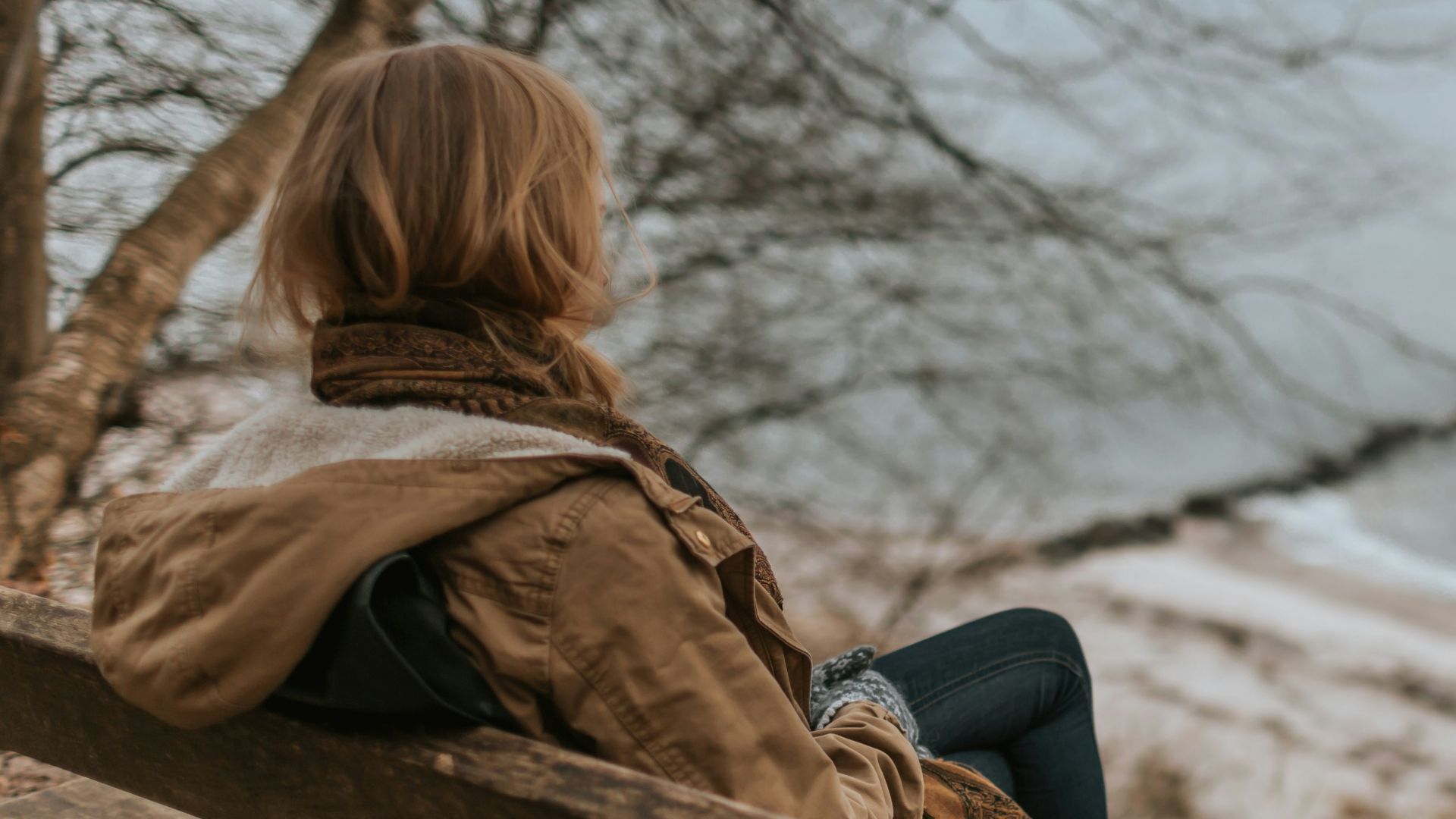 woman sitting on brown wooden bench