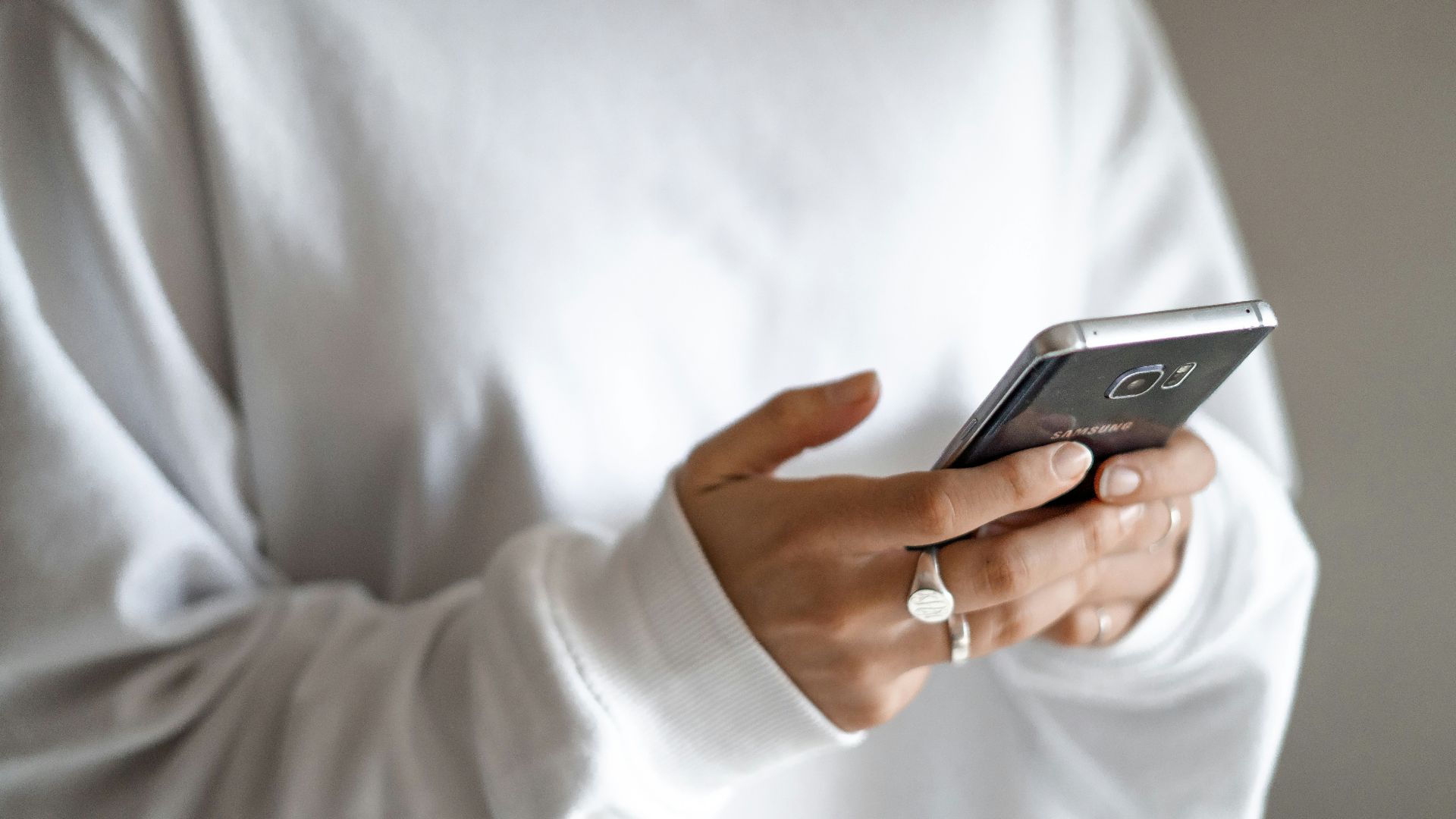 person in white long sleeve shirt holding black smartphone