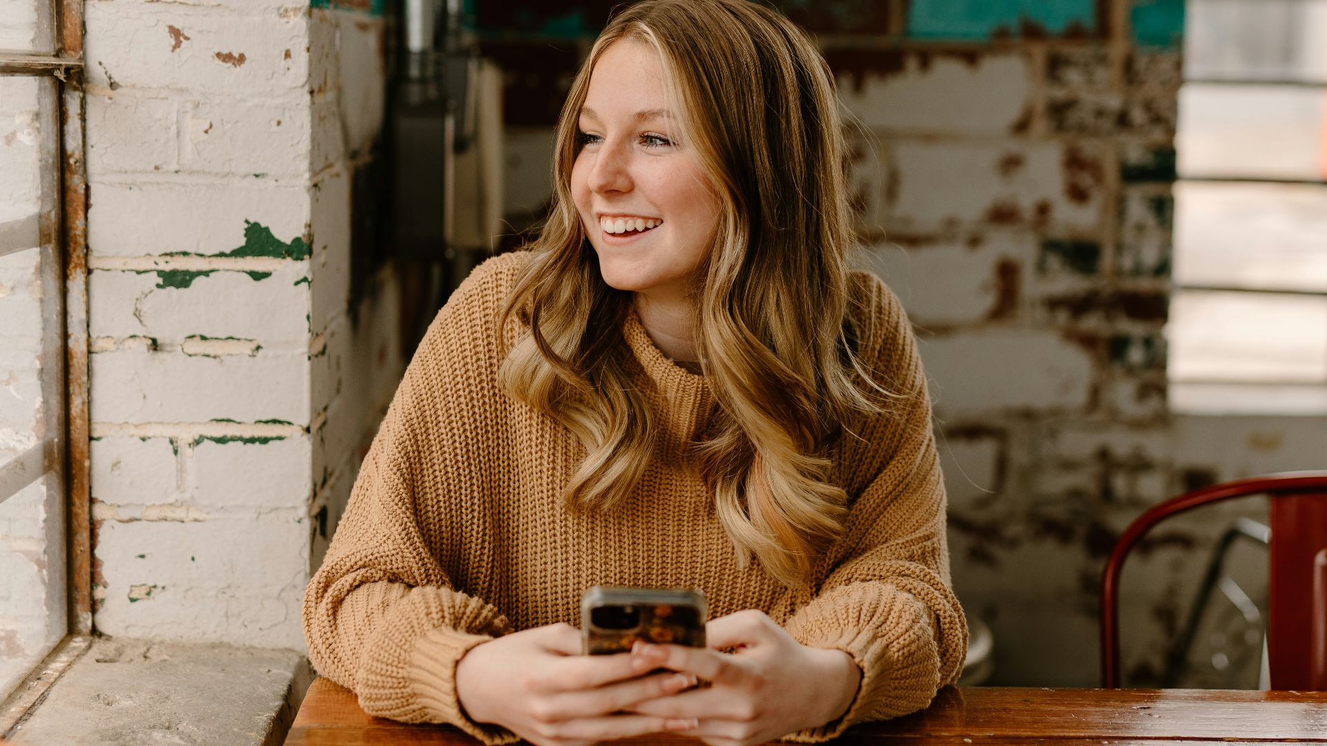 a woman sitting at a table with a cell phone