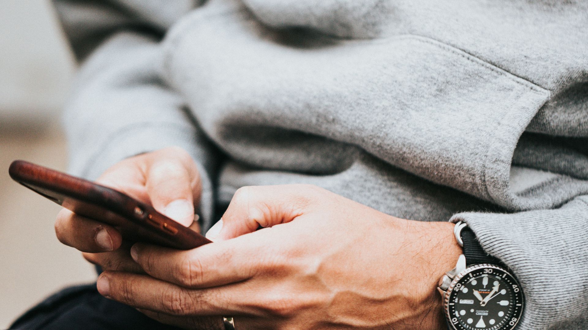 person in gray sweater wearing black and silver chronograph watch