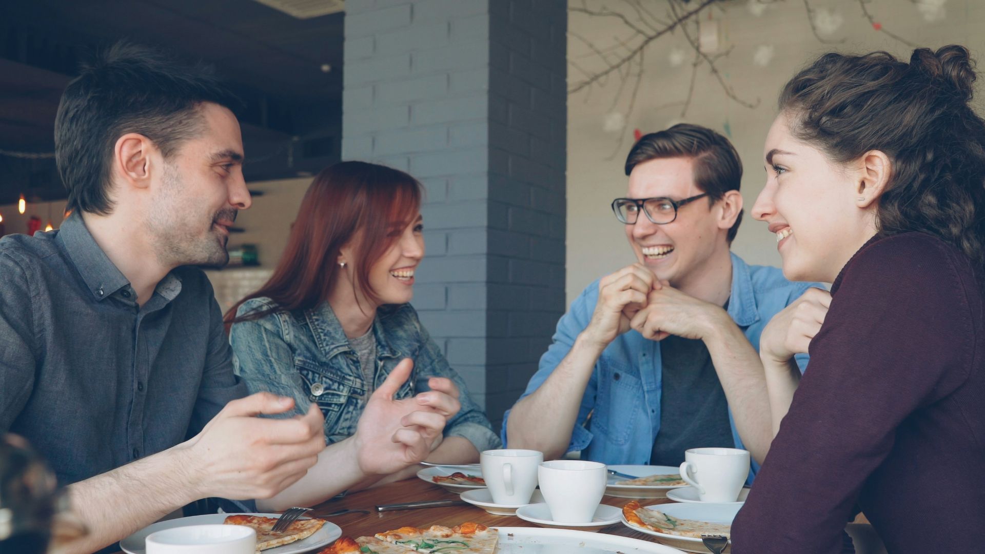 Friends enjoy pizza and conversation at a restaurant.