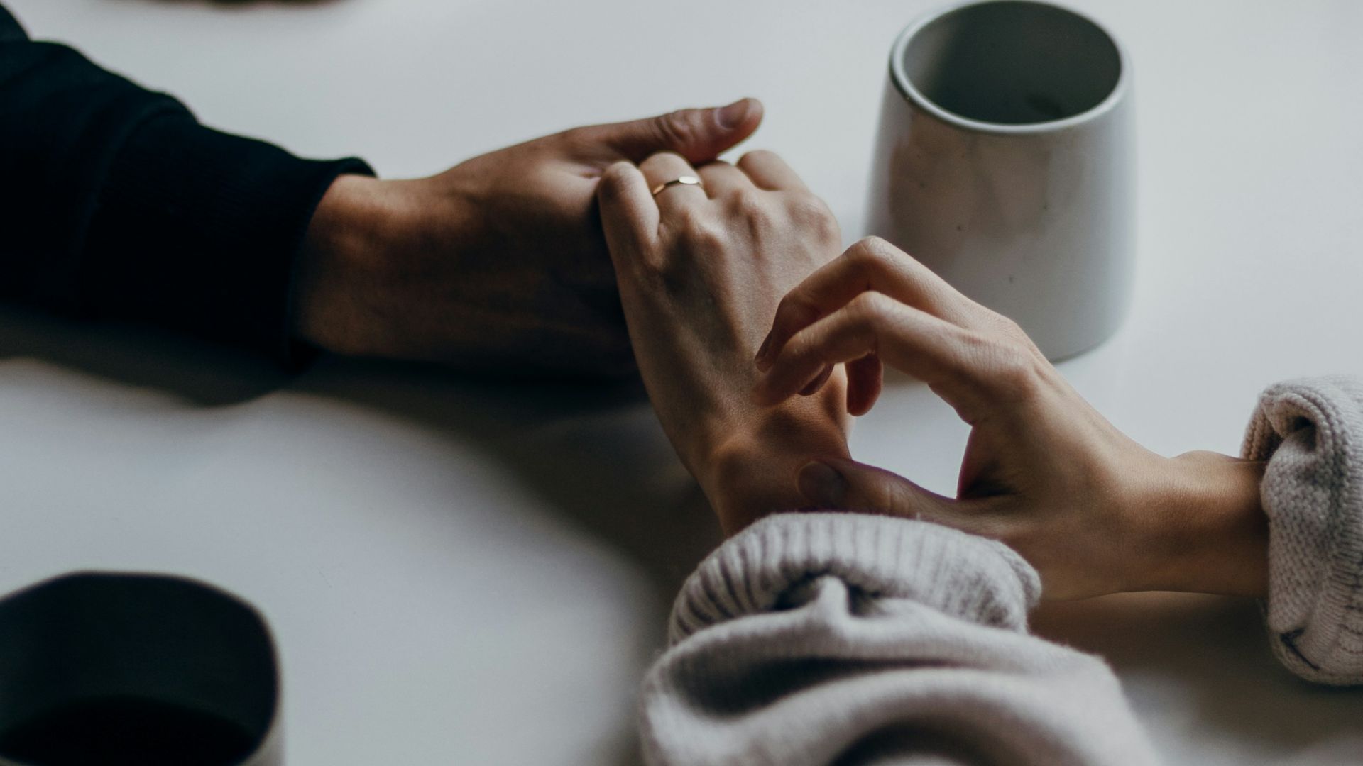 person in black long sleeve shirt holding white ceramic mug