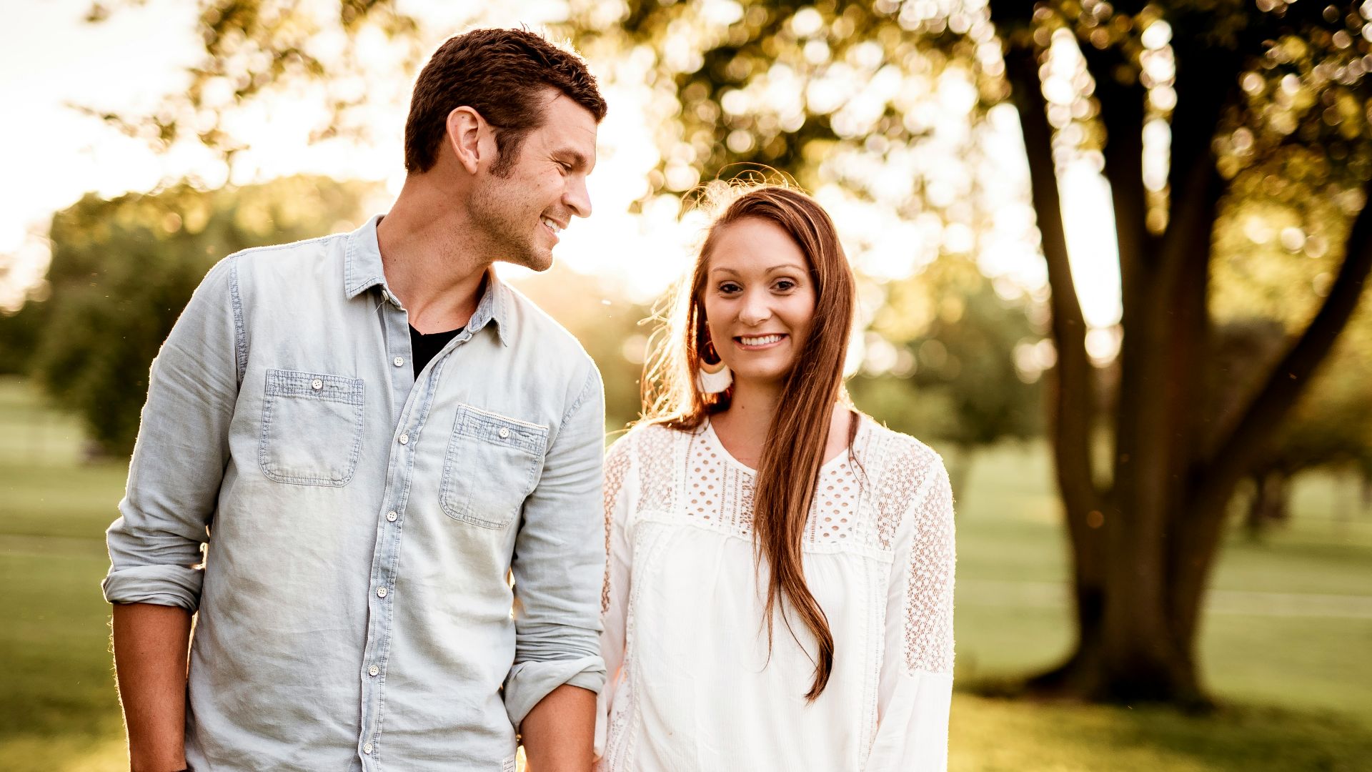 man holding hand of woman standing near tree