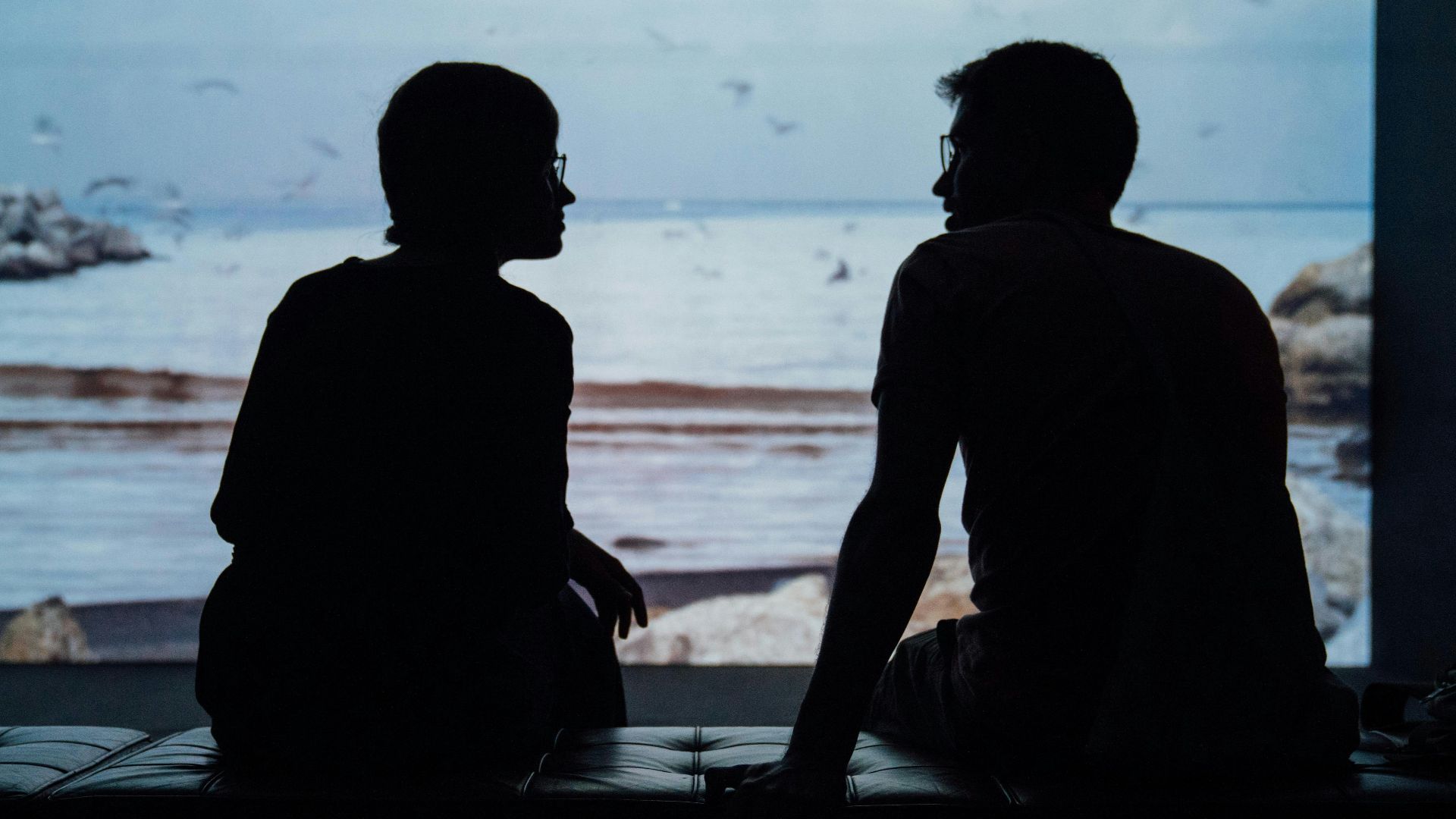 silhouette of man and woman sitting on ottoman