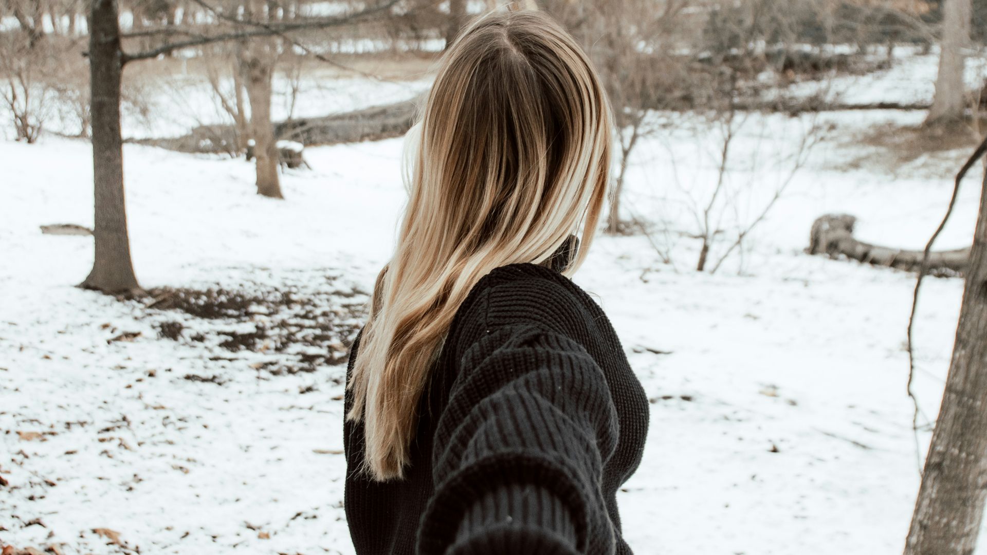 woman in black sweater standing on snow covered ground during daytime