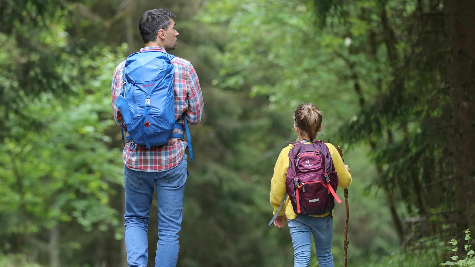 man in blue jacket and blue denim jeans walking on dirt road during daytime