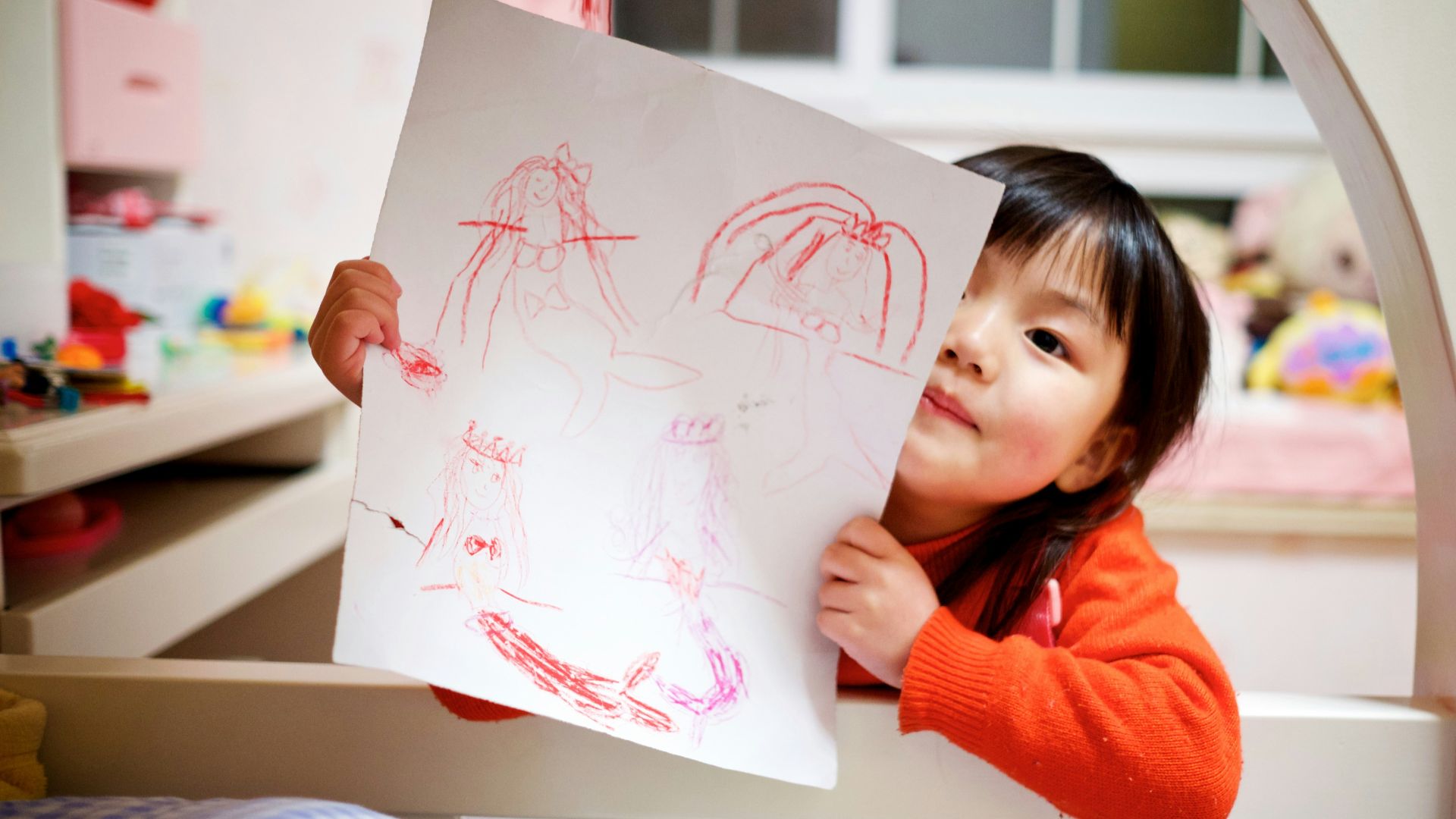 girl holding paper with drawing