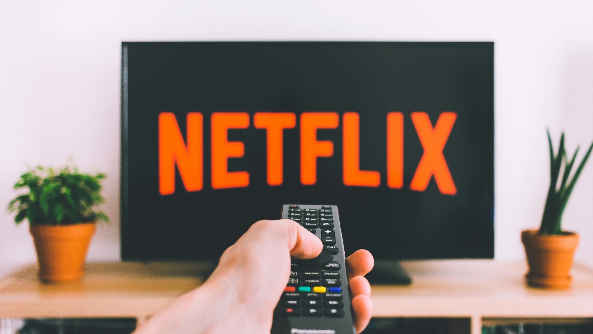 person holding remote pointing at TV