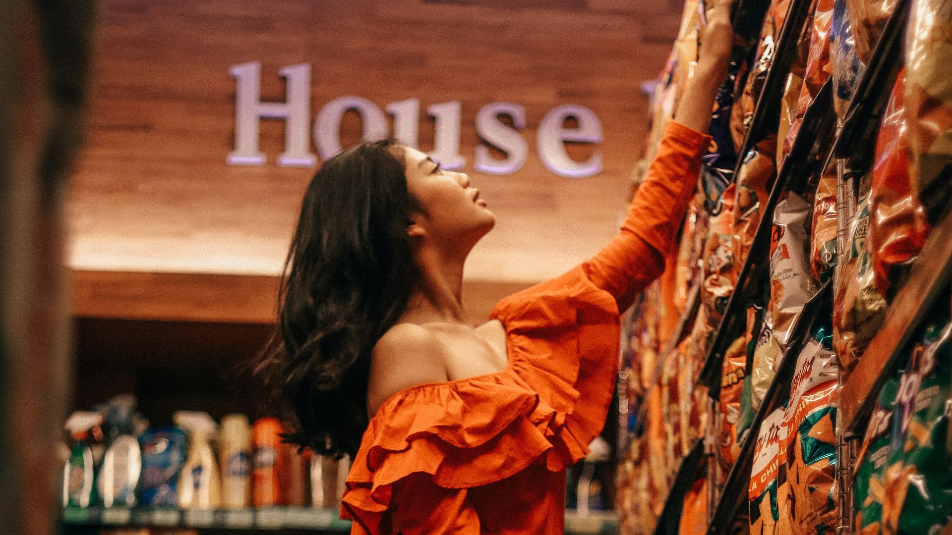 woman reaching chip packs inside store