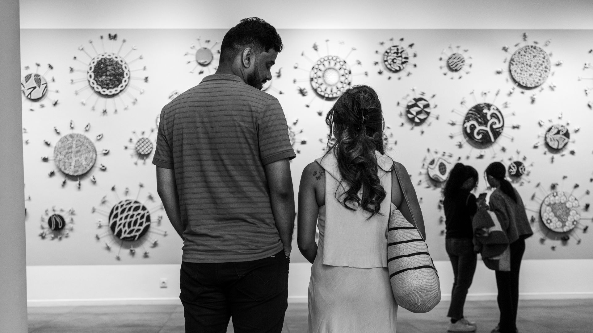 Couple viewing circular art on gallery wall
