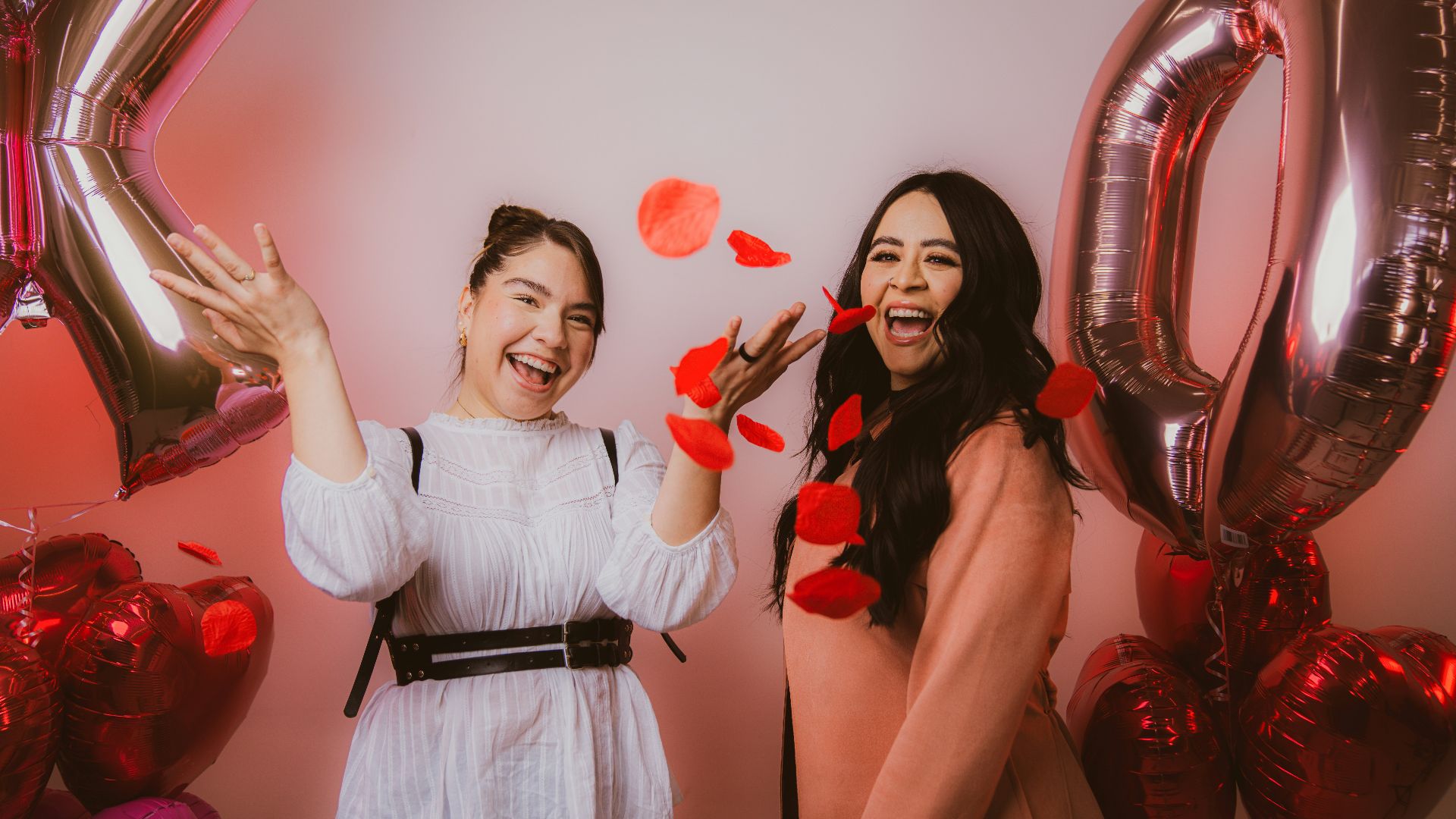 two women standing next to each other near balloons
