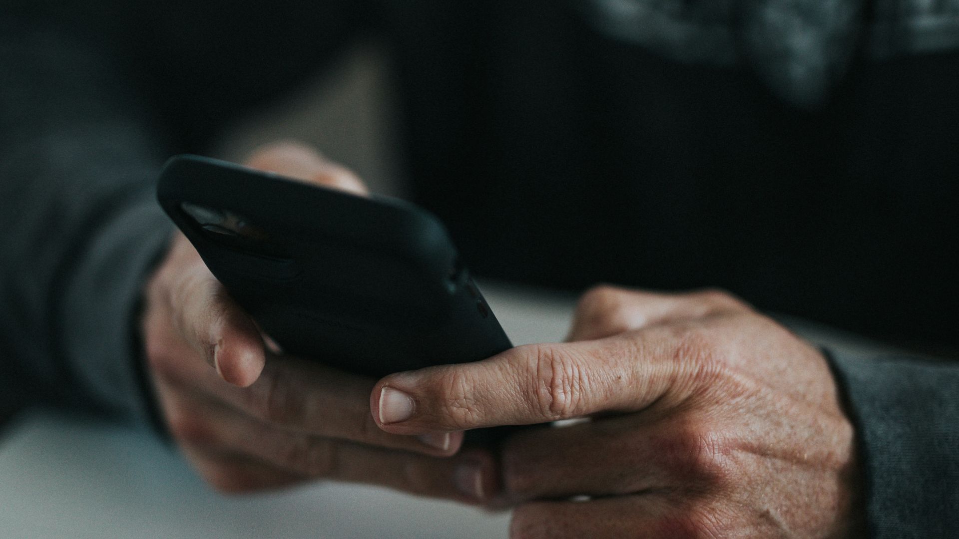 person holding black smartphone on white paper