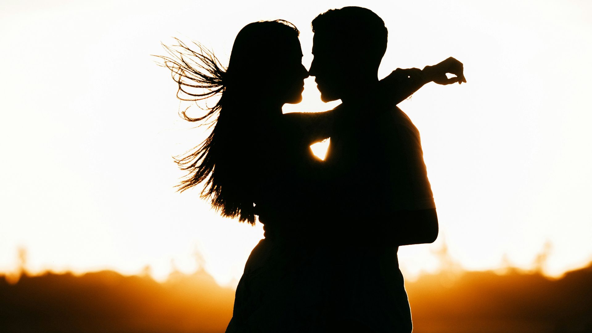 silhouette of woman standing on beach during sunset