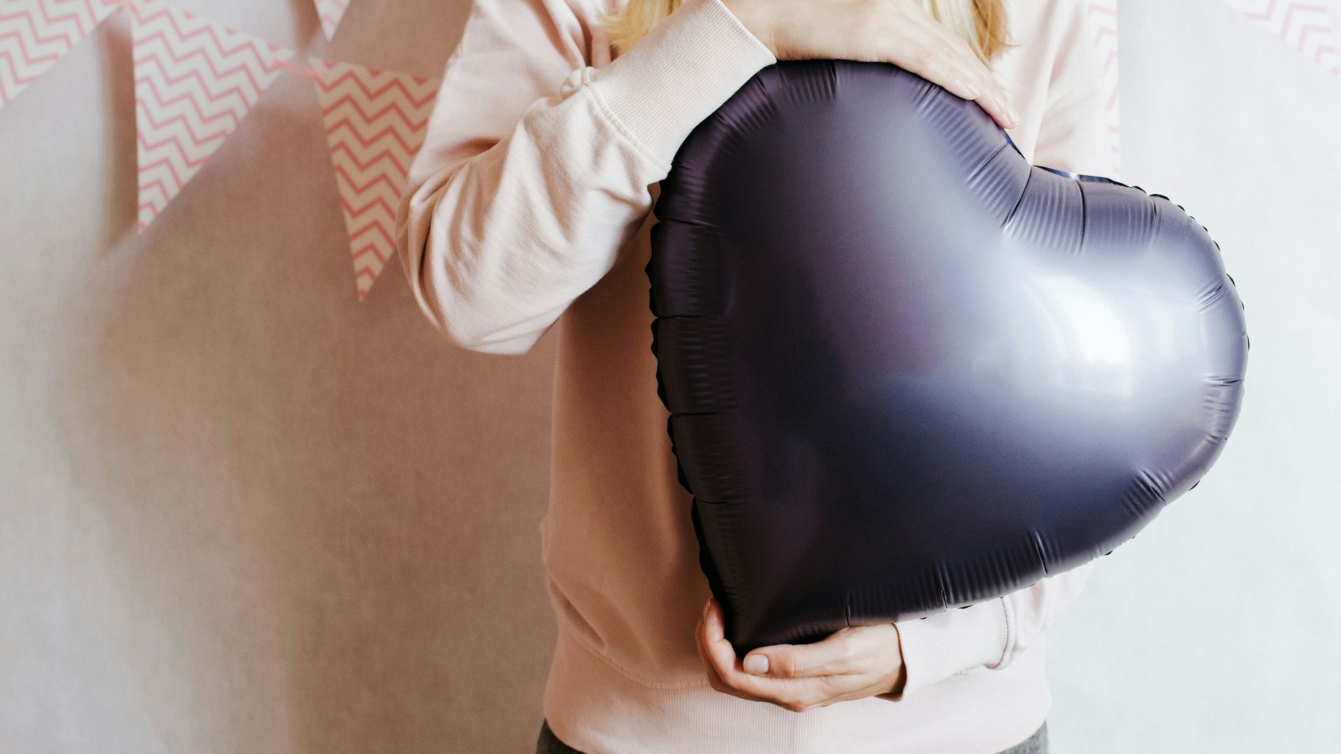 Person holding a dark purple heart-shaped balloon