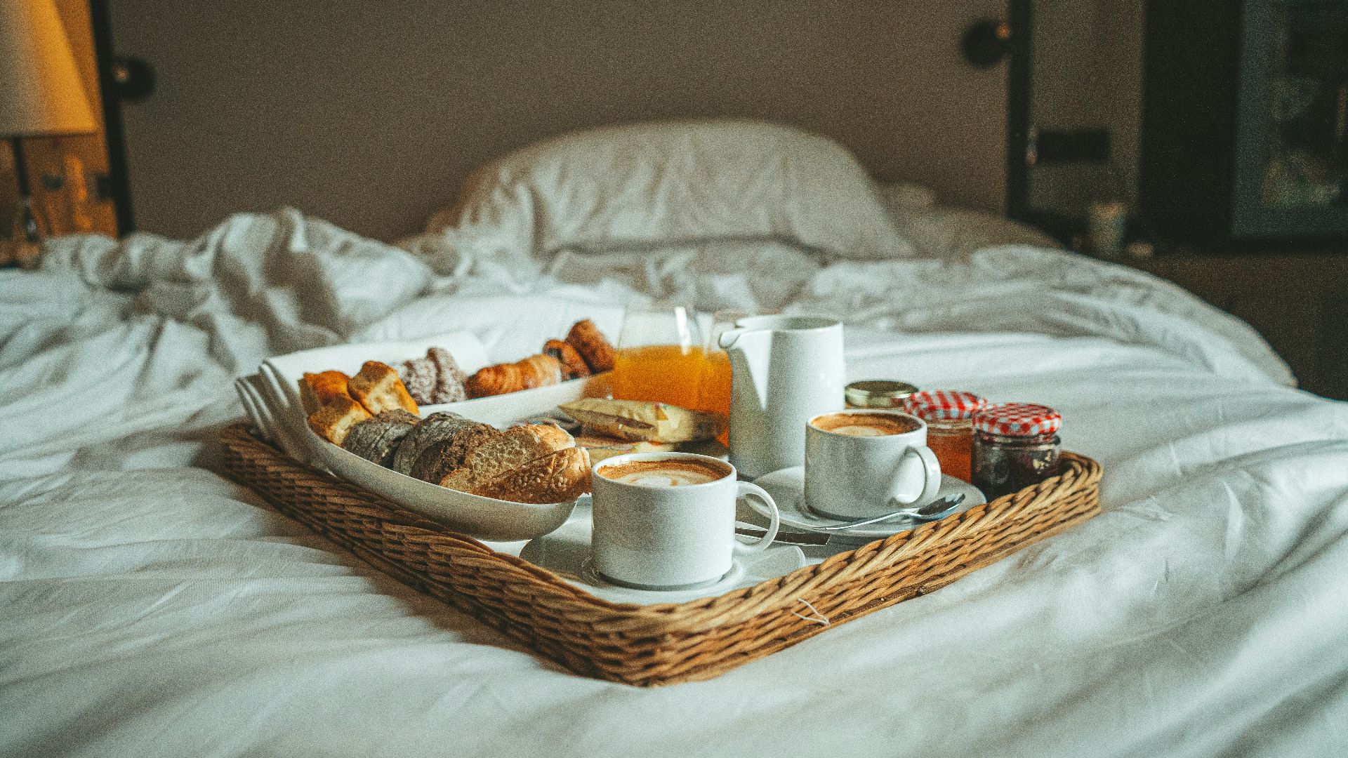 a tray of breakfast on a bed with white sheets