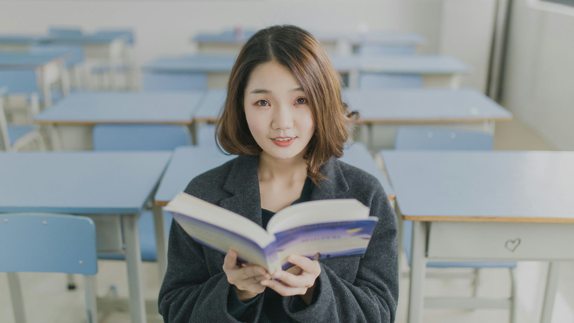 woman reading book sitting on chair in room