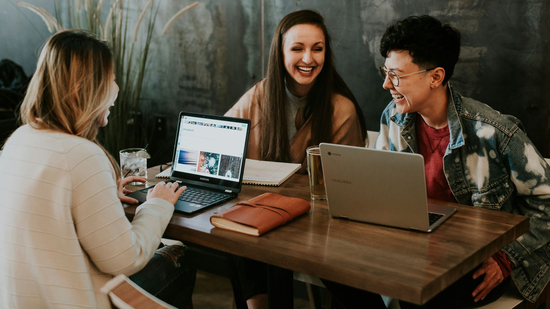 three people sitting in front of table laughing together