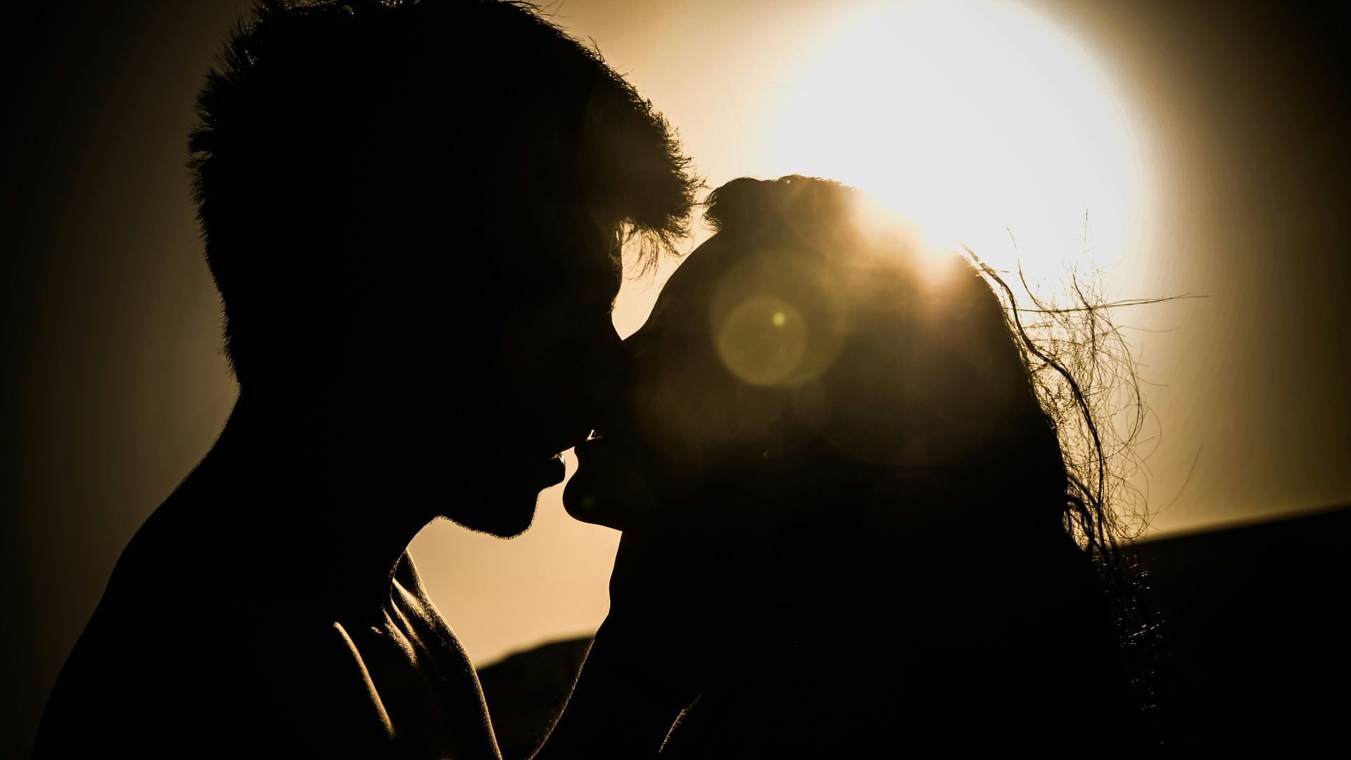 man and woman kissing under the sun